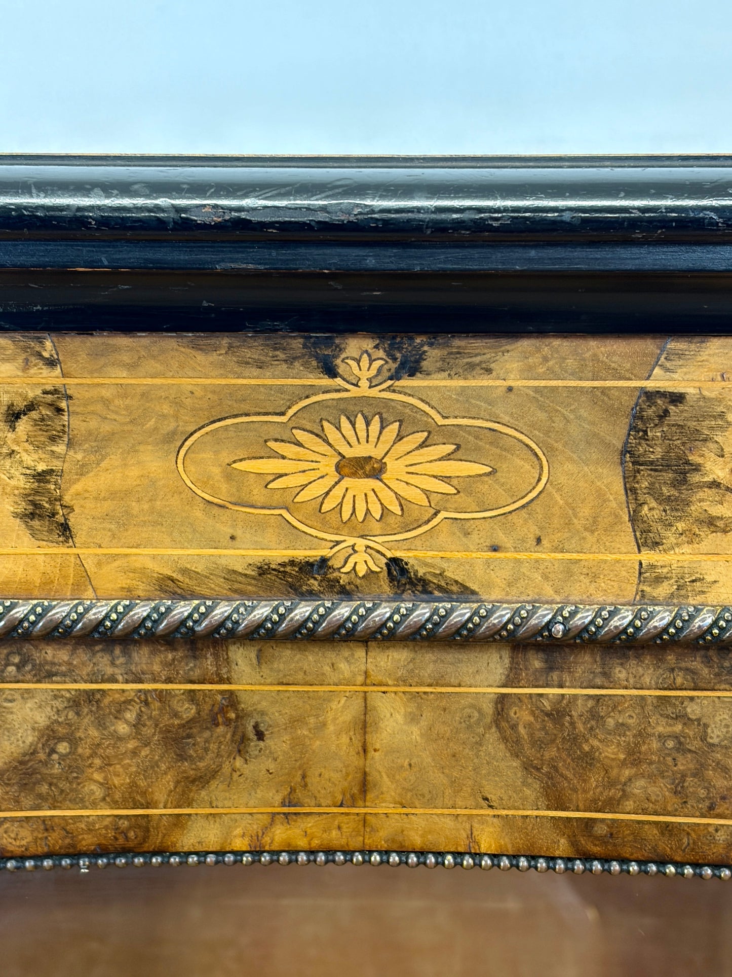 Close-up of a wooden panel with decorative carvings and a sunflower emblem against a blue sky.