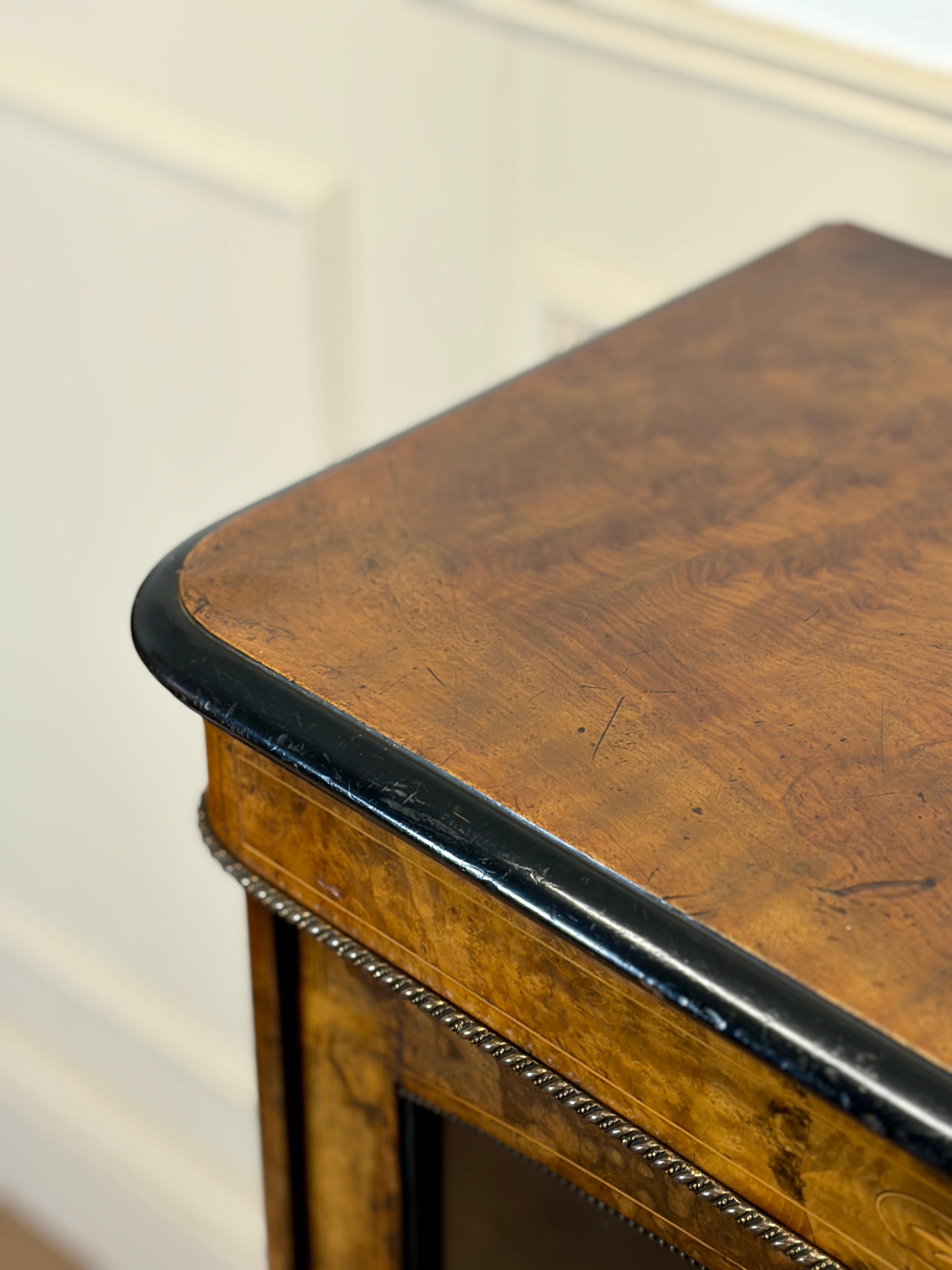 Close-up of a wooden table with a black edge against a white wall.