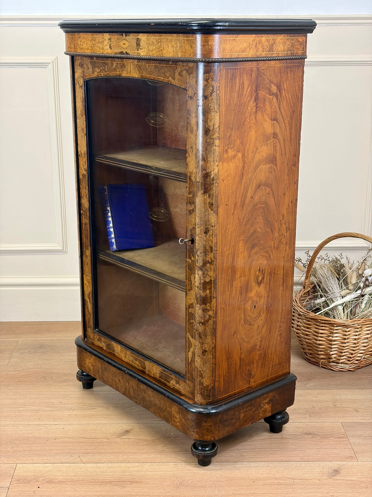 Wooden display cabinet with glass doors on a wooden floor.