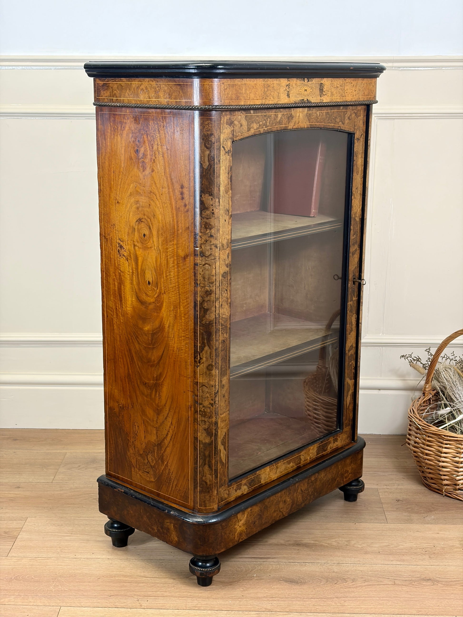 Wooden display cabinet with glass door on a wooden floor.