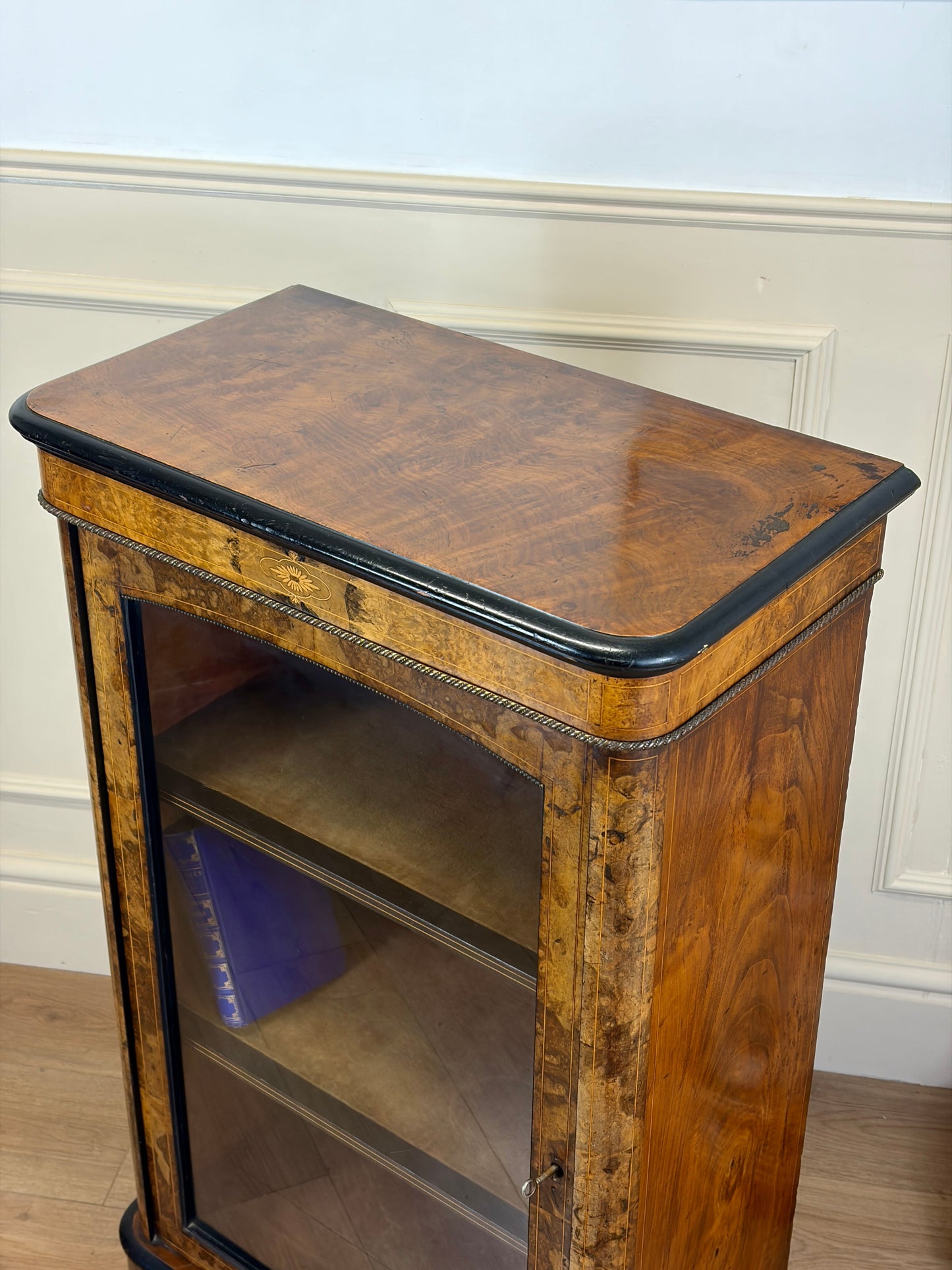 Wooden side table with a glass shelf against a white wall.