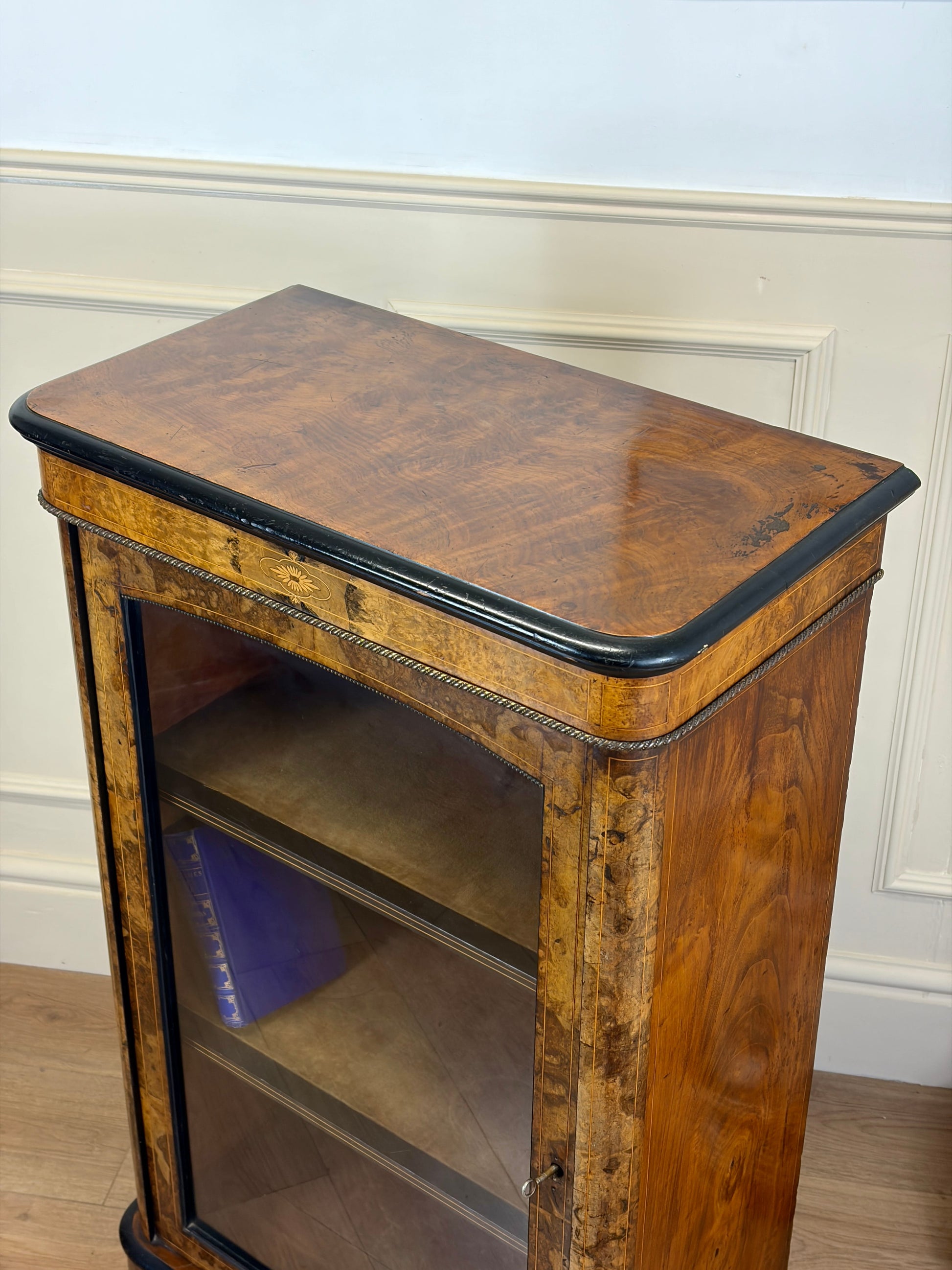 Wooden side table with a glass shelf against a white wall.