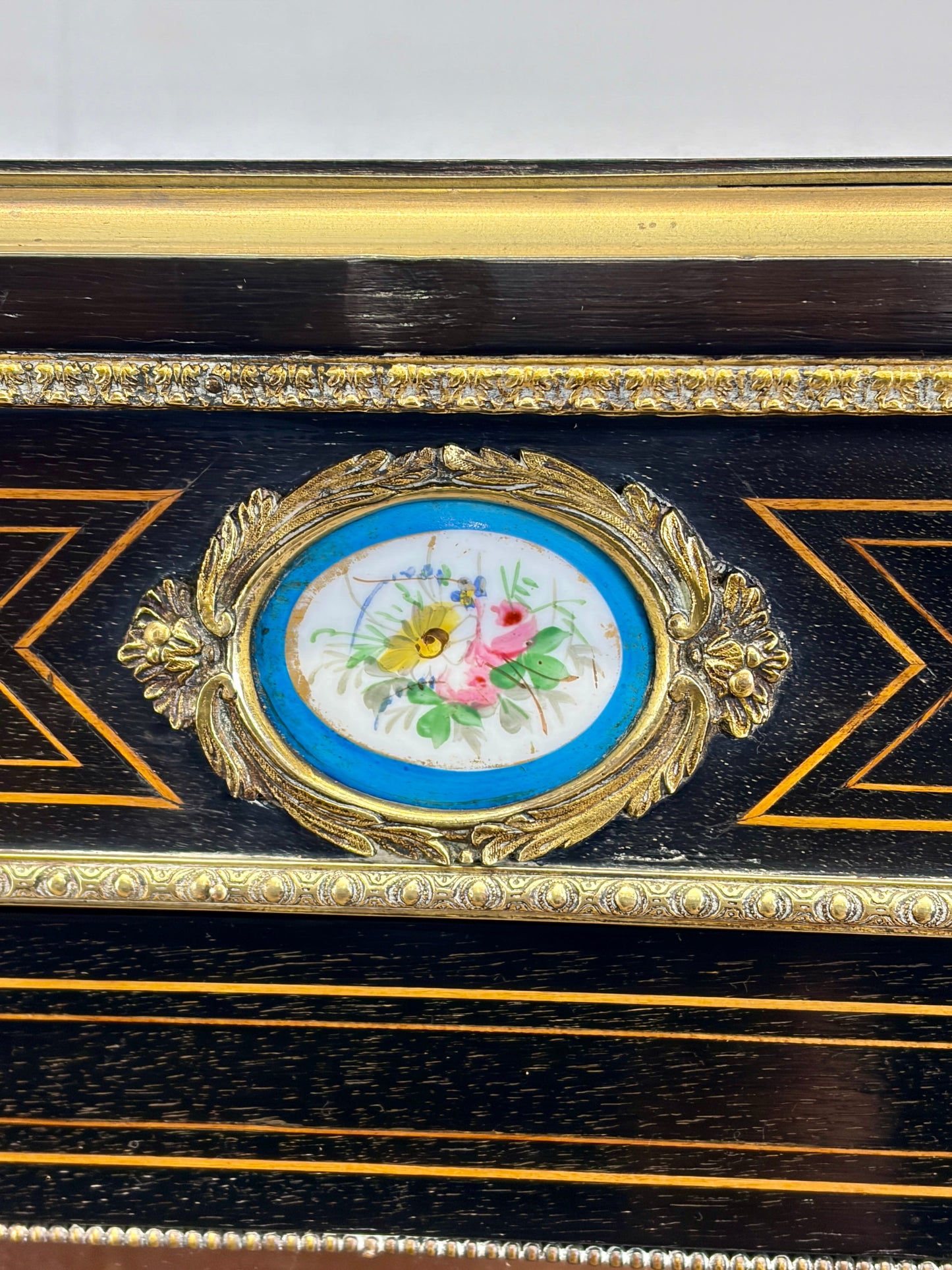 Decorative wooden box with gold accents and a floral emblem on a white background