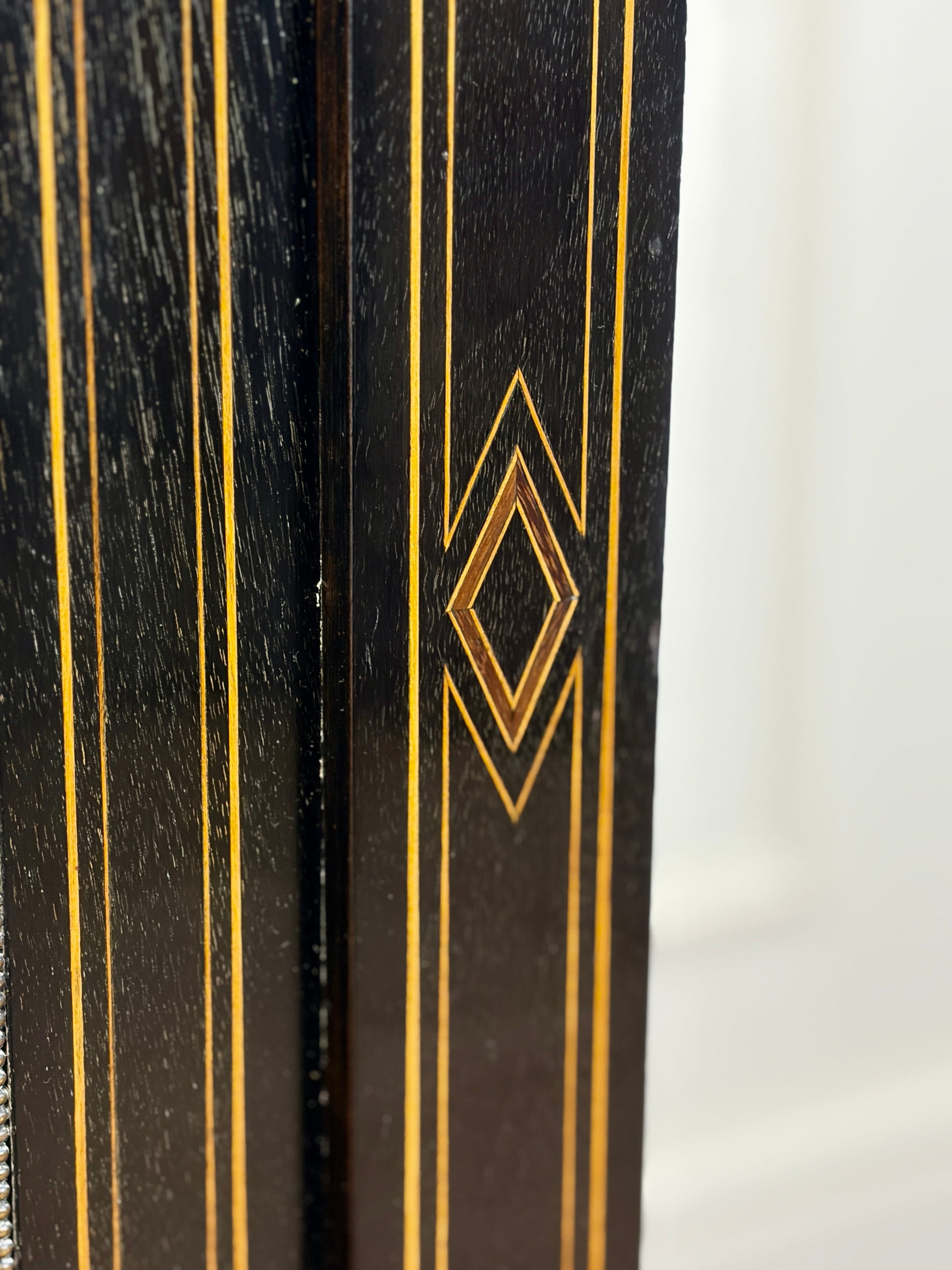 Close-up of a black object with gold geometric patterns on a white background