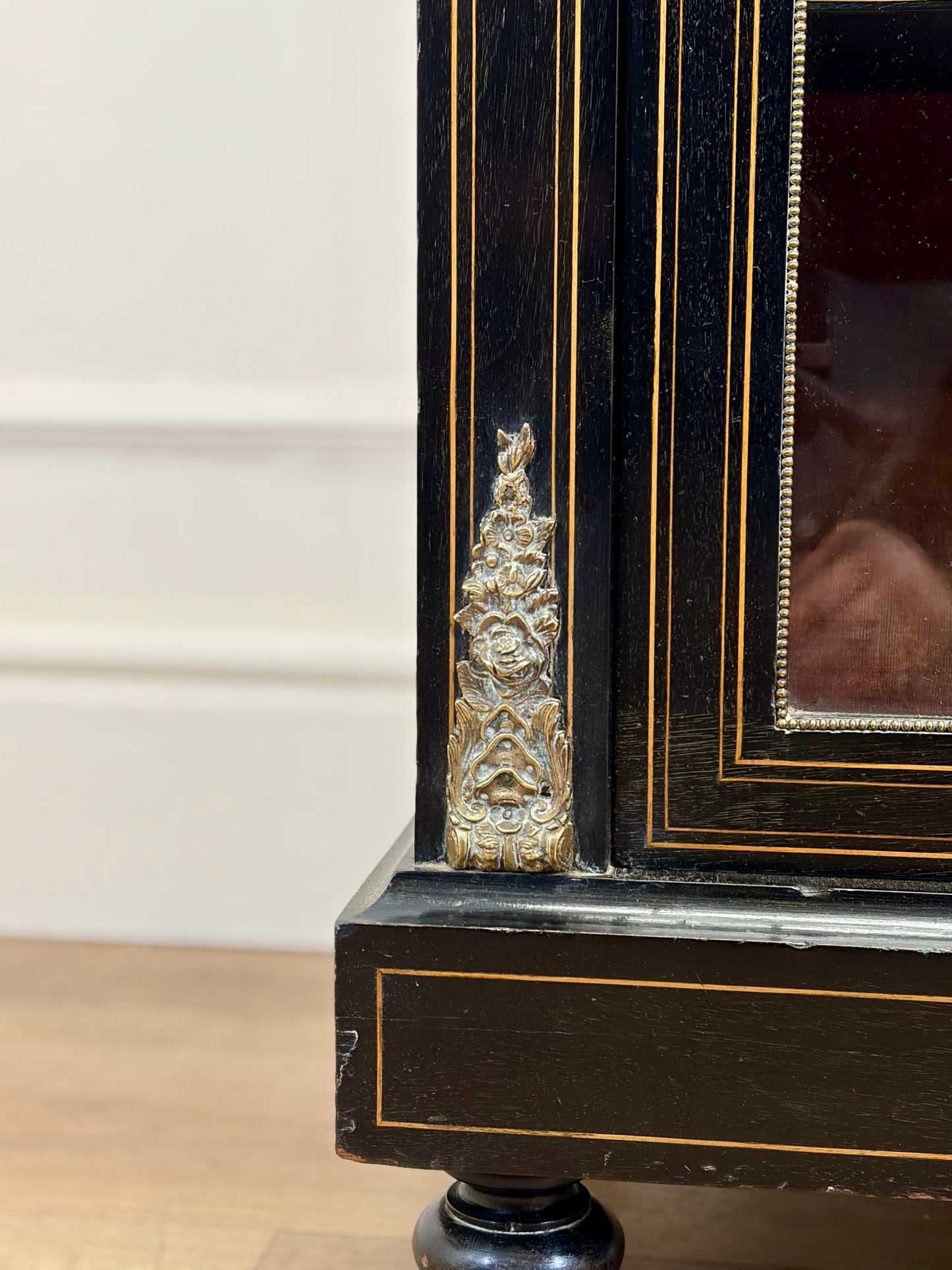 Close-up of an ornate black frame with gold detailing on a white wall background.