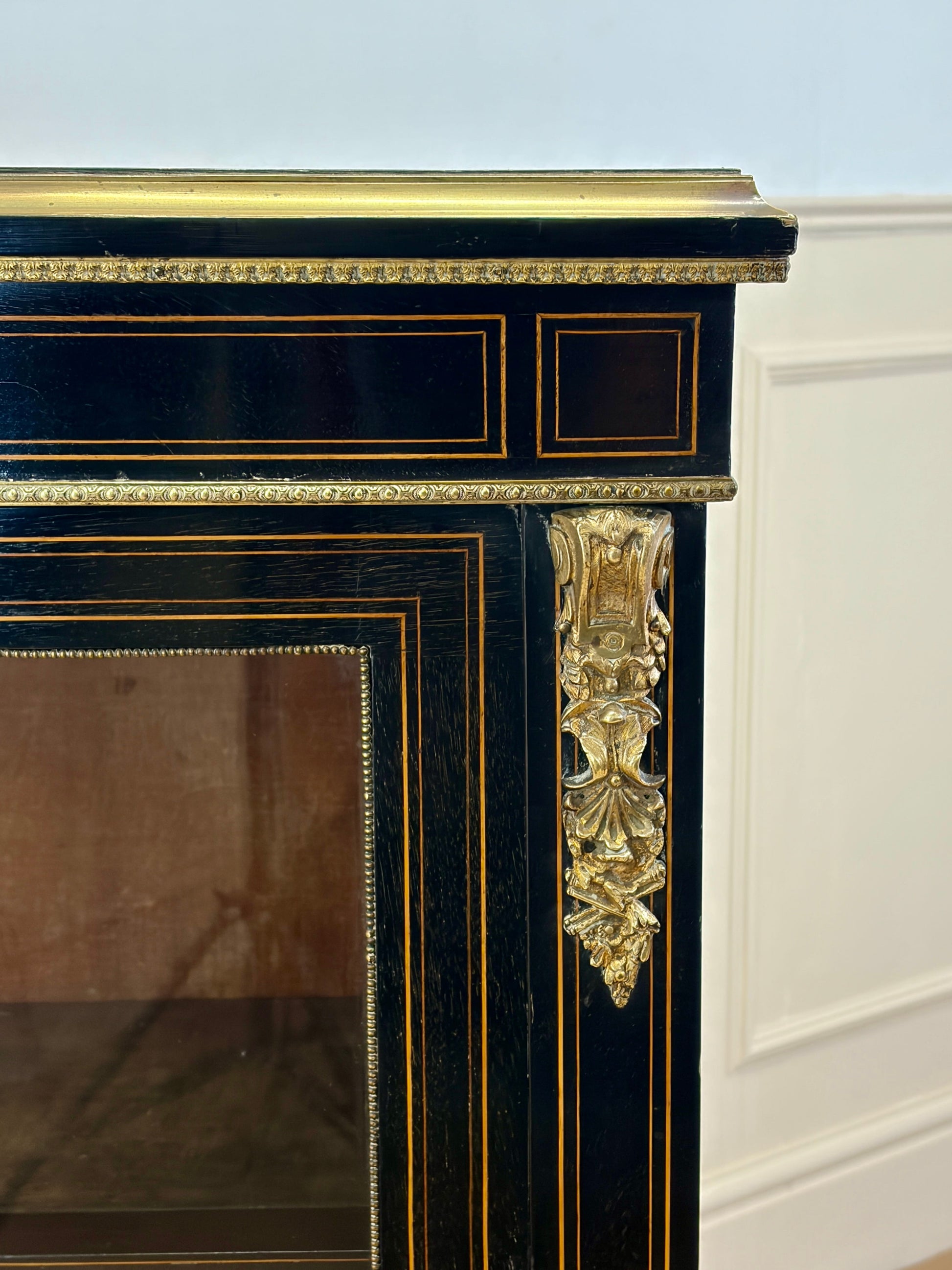 Decorative fireplace with black and gold finish on a white wall.