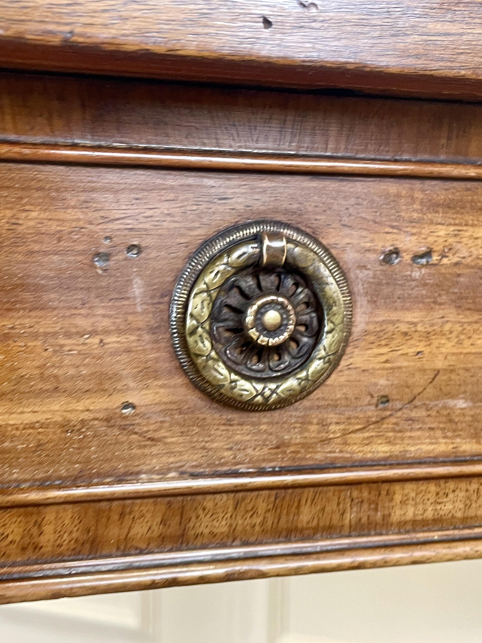 Close-up of a wooden drawer with a decorative brass handle