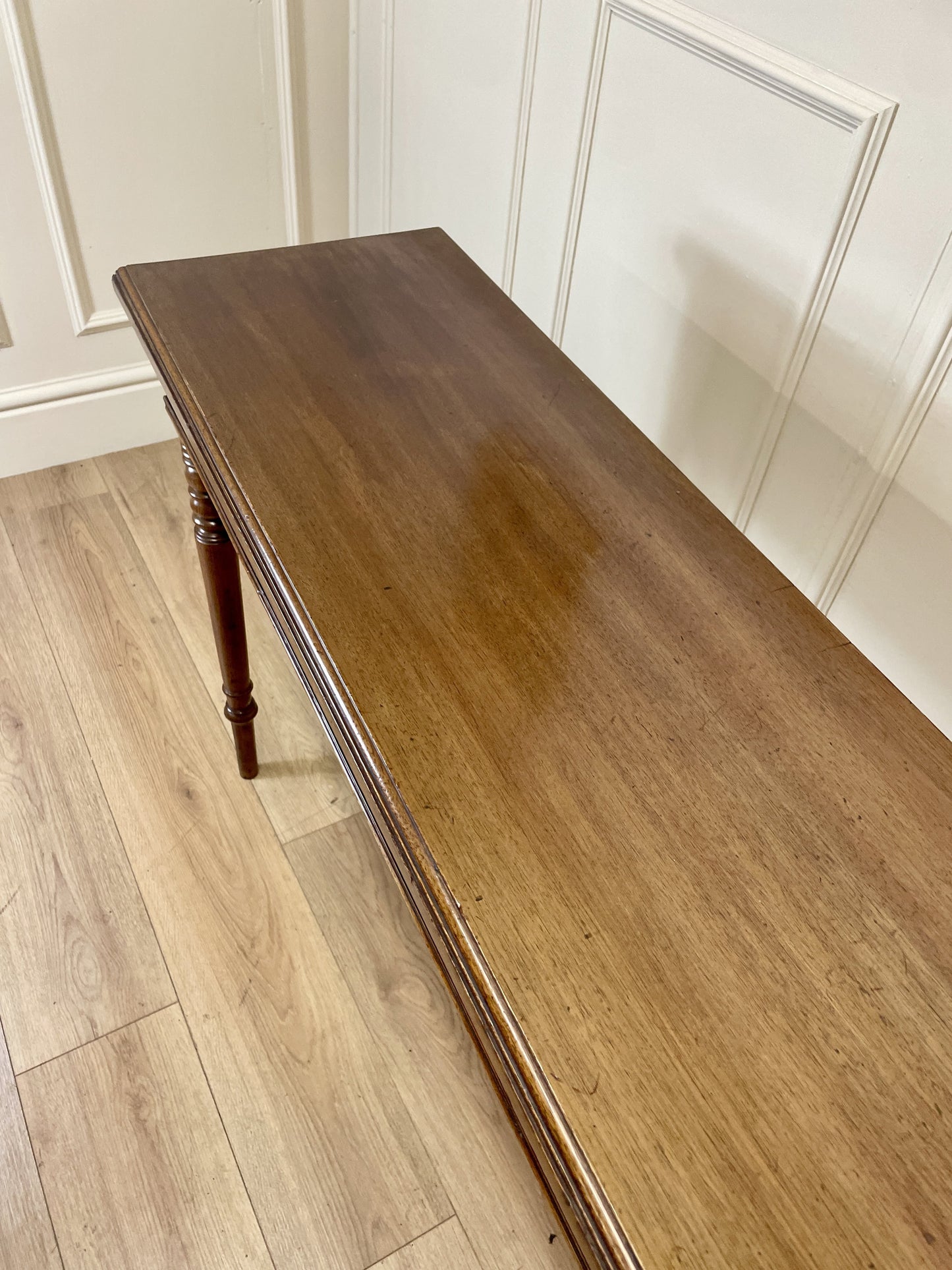 Wooden bench against a white paneled wall