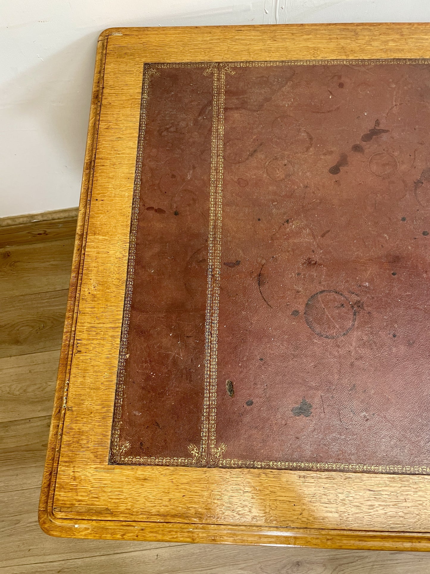 Close-up of an old book with a brown leather cover on a wooden floor.