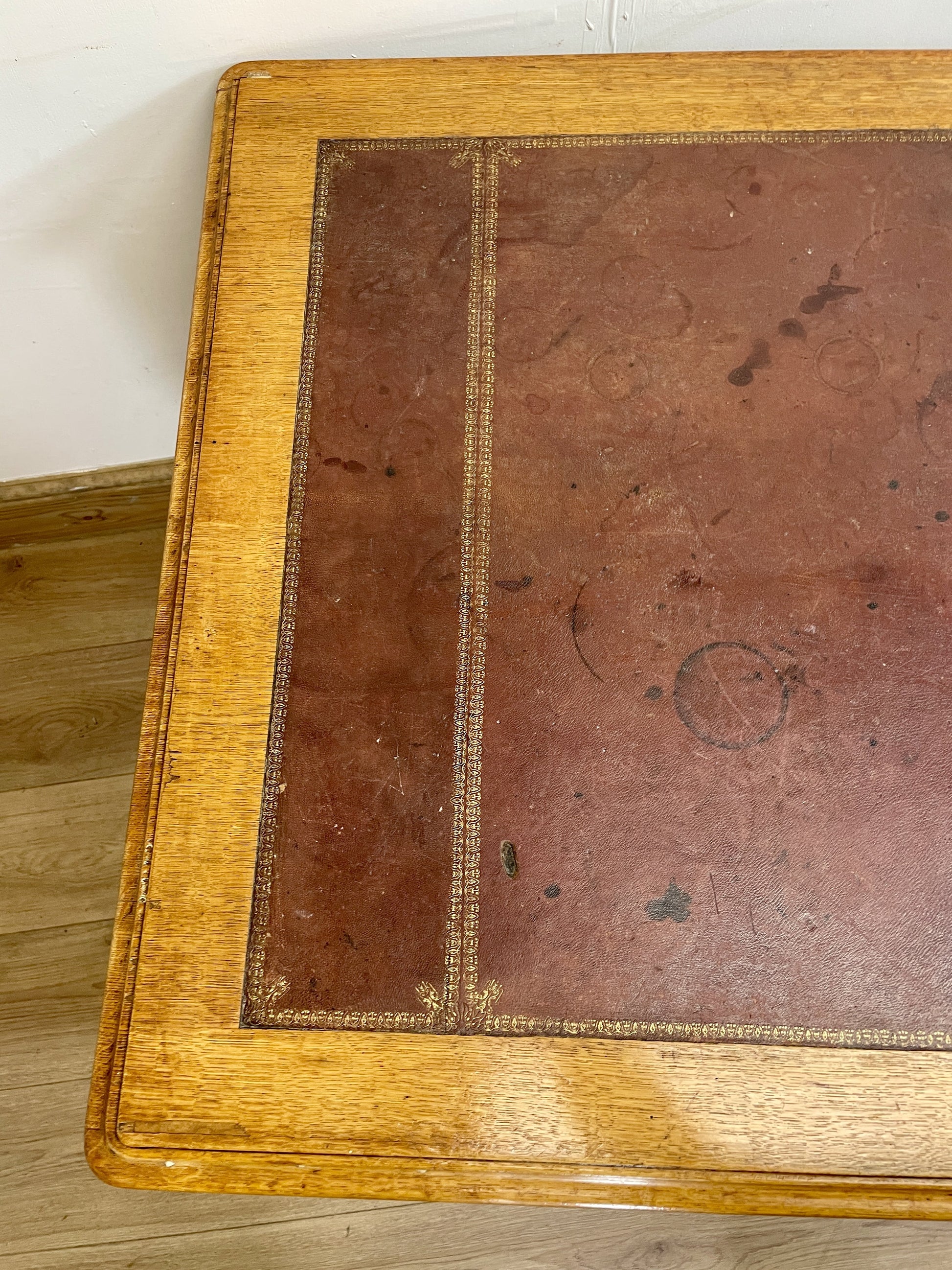 Close-up of an old book with a brown leather cover on a wooden floor.