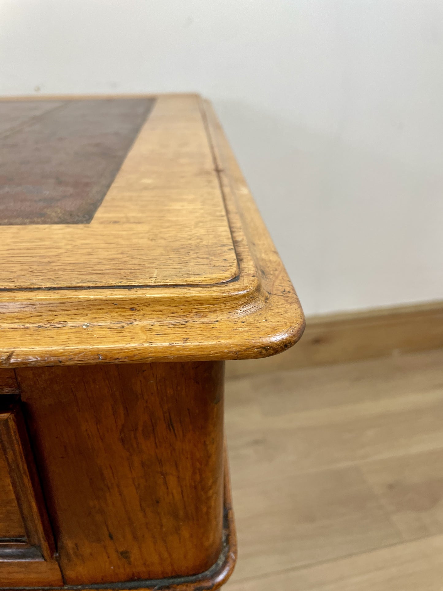 Wooden desk with a glass top on a wooden floor.