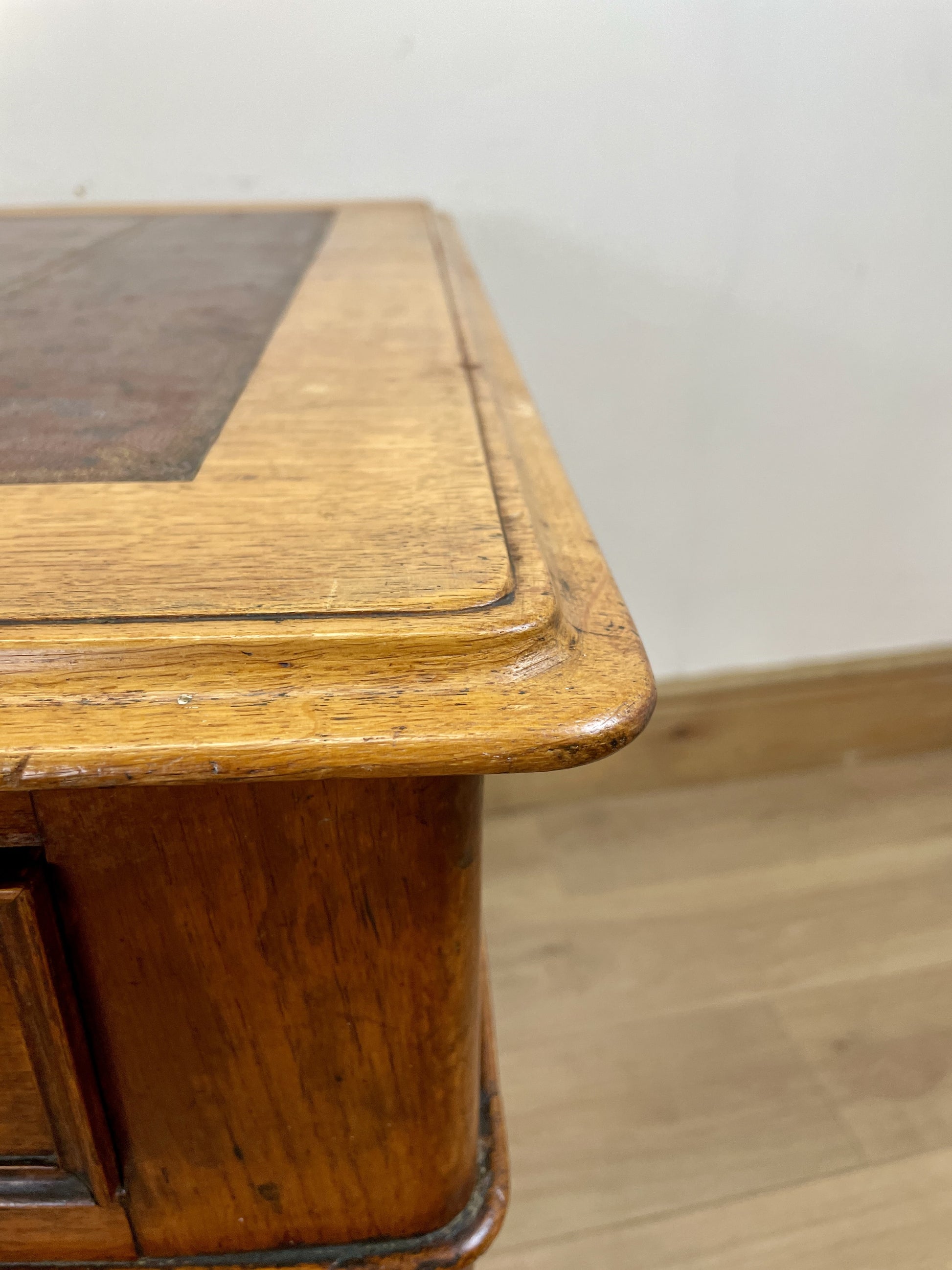 Wooden desk with a glass top on a wooden floor.
