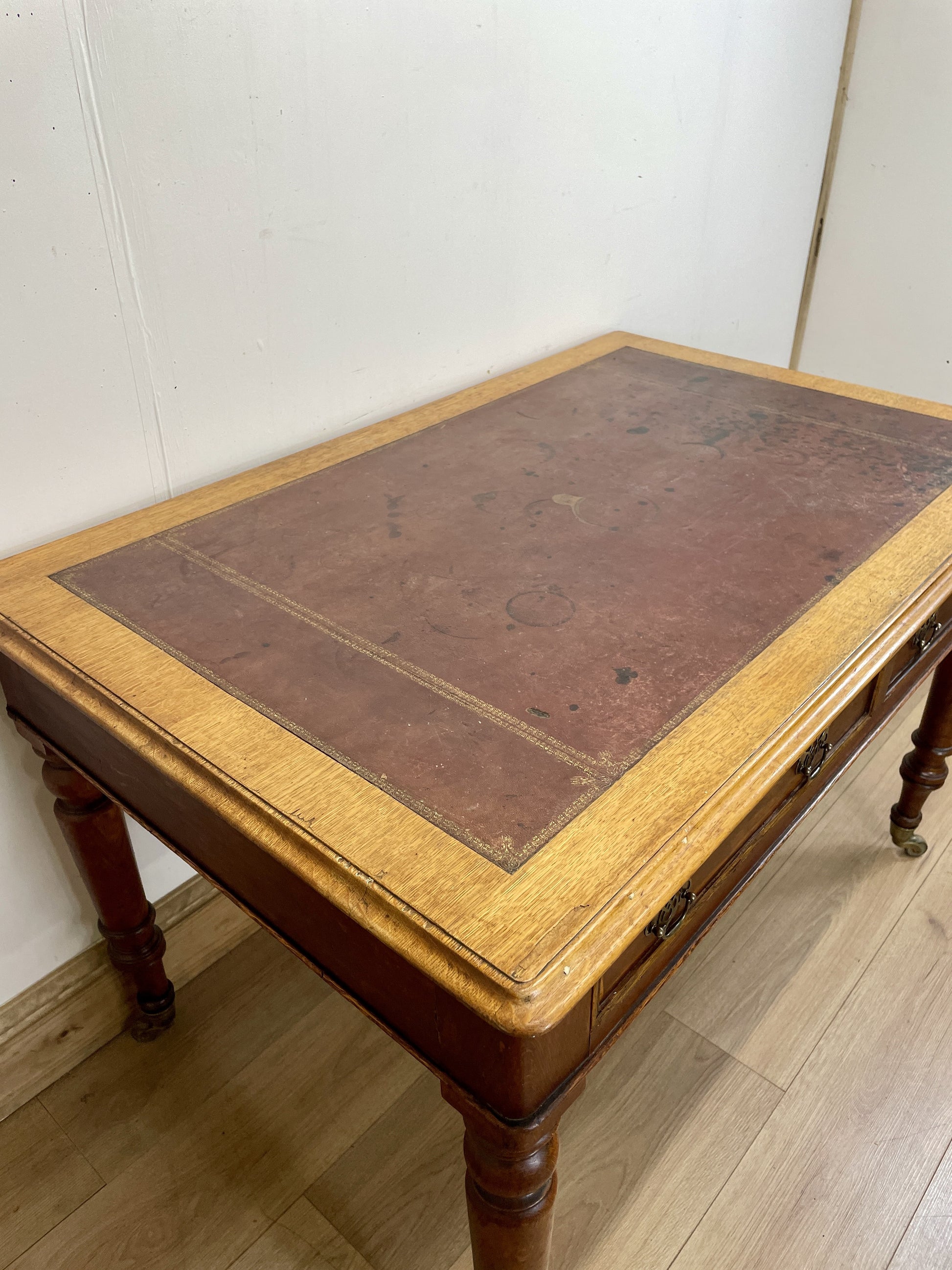 Wooden desk with leather surface on a wooden floor.
