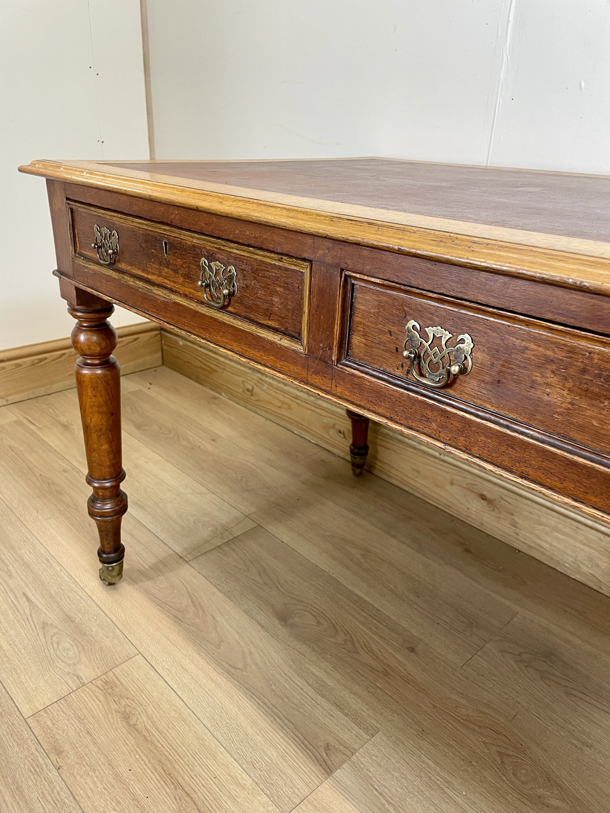 Wooden desk with two drawers on a wooden floor.