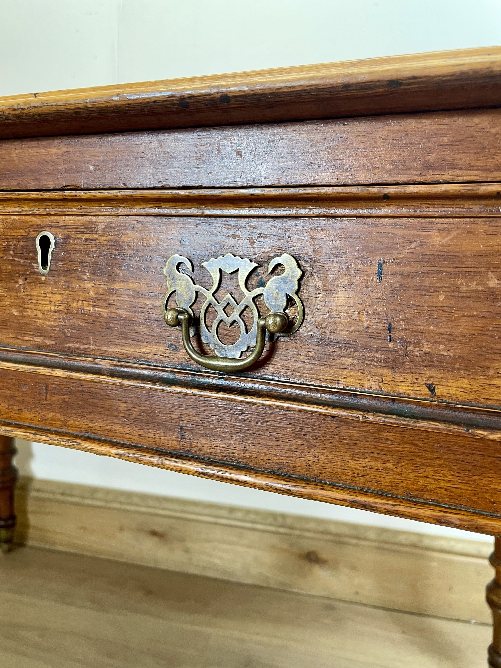 Close-up of a wooden drawer with a decorative brass handle.