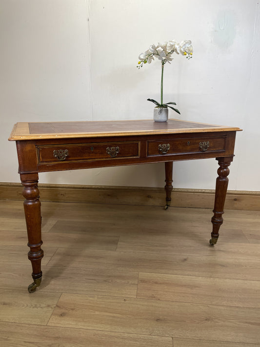 Wooden desk with a vase of flowers on a wooden floor against a white wall