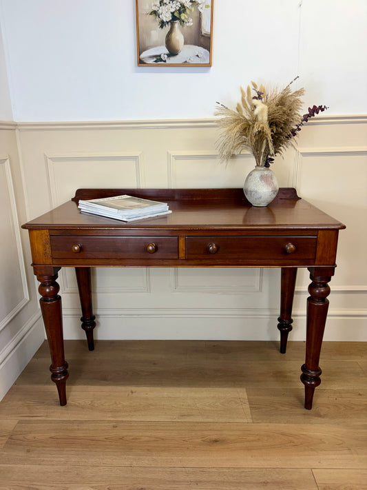 Wooden console table with a vase and books on a wooden floor.