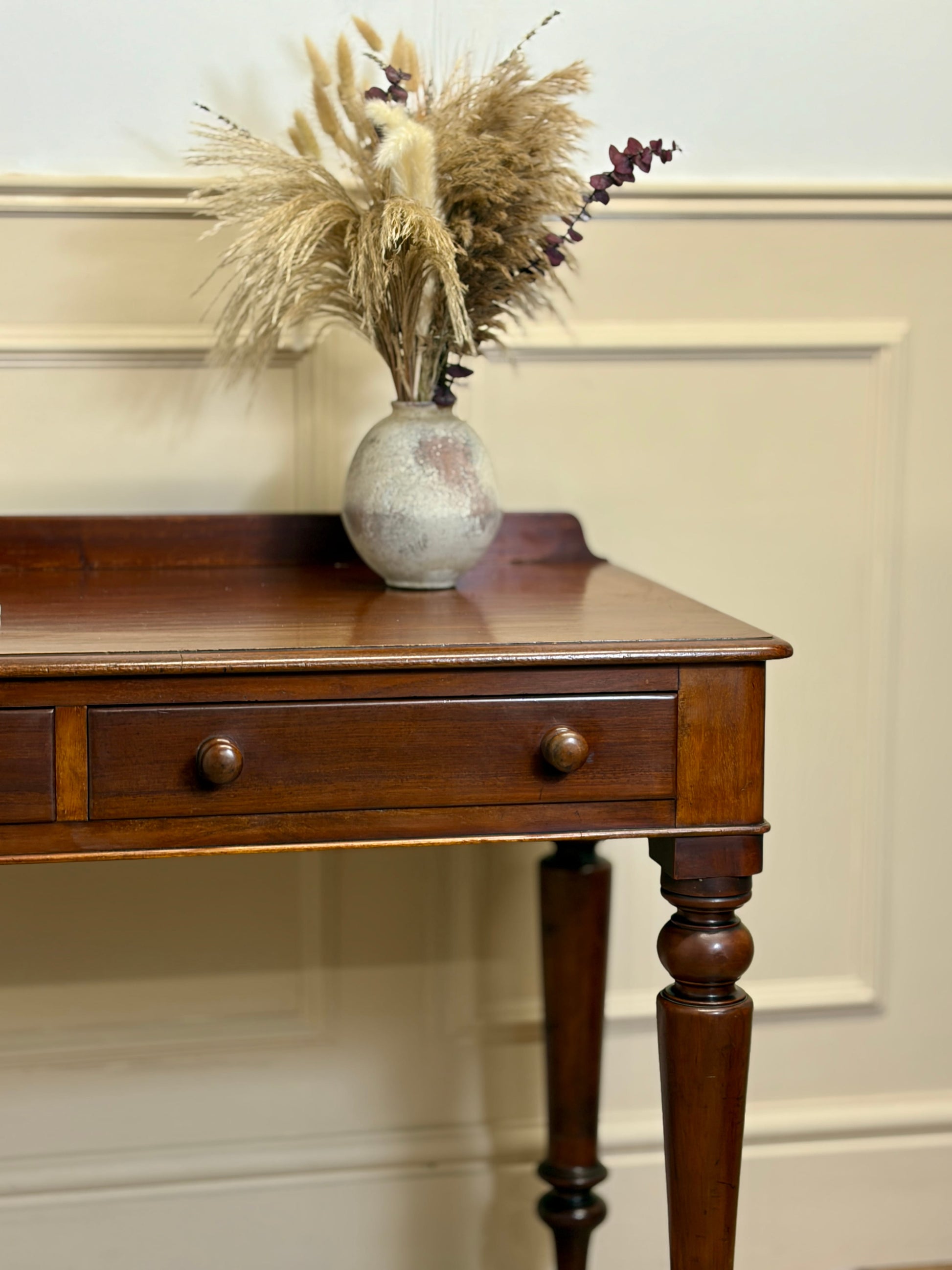 Wooden side table with a vase of dried flowers on a neutral wall background