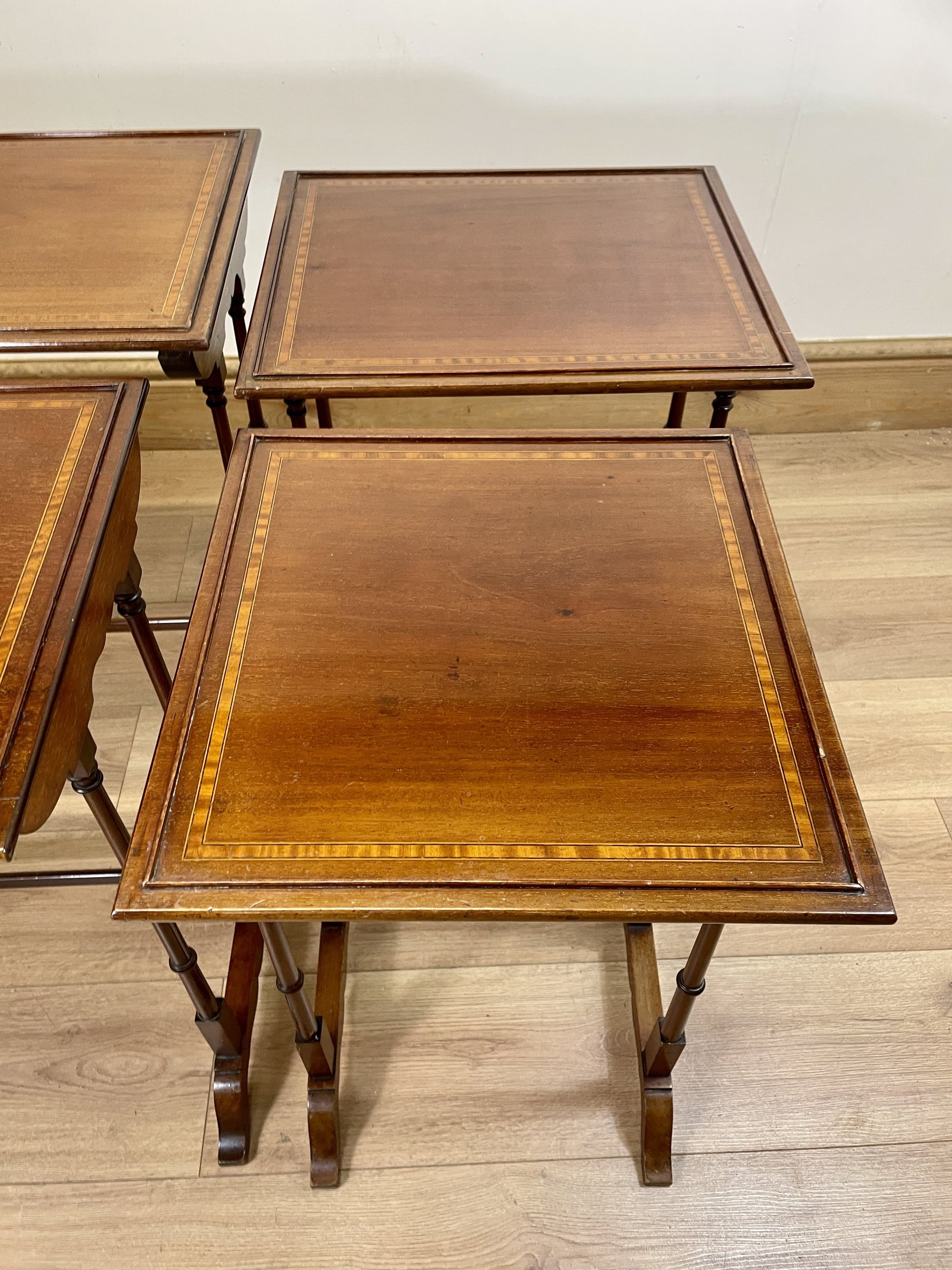 Set of three wooden nesting tables on a wooden floor.