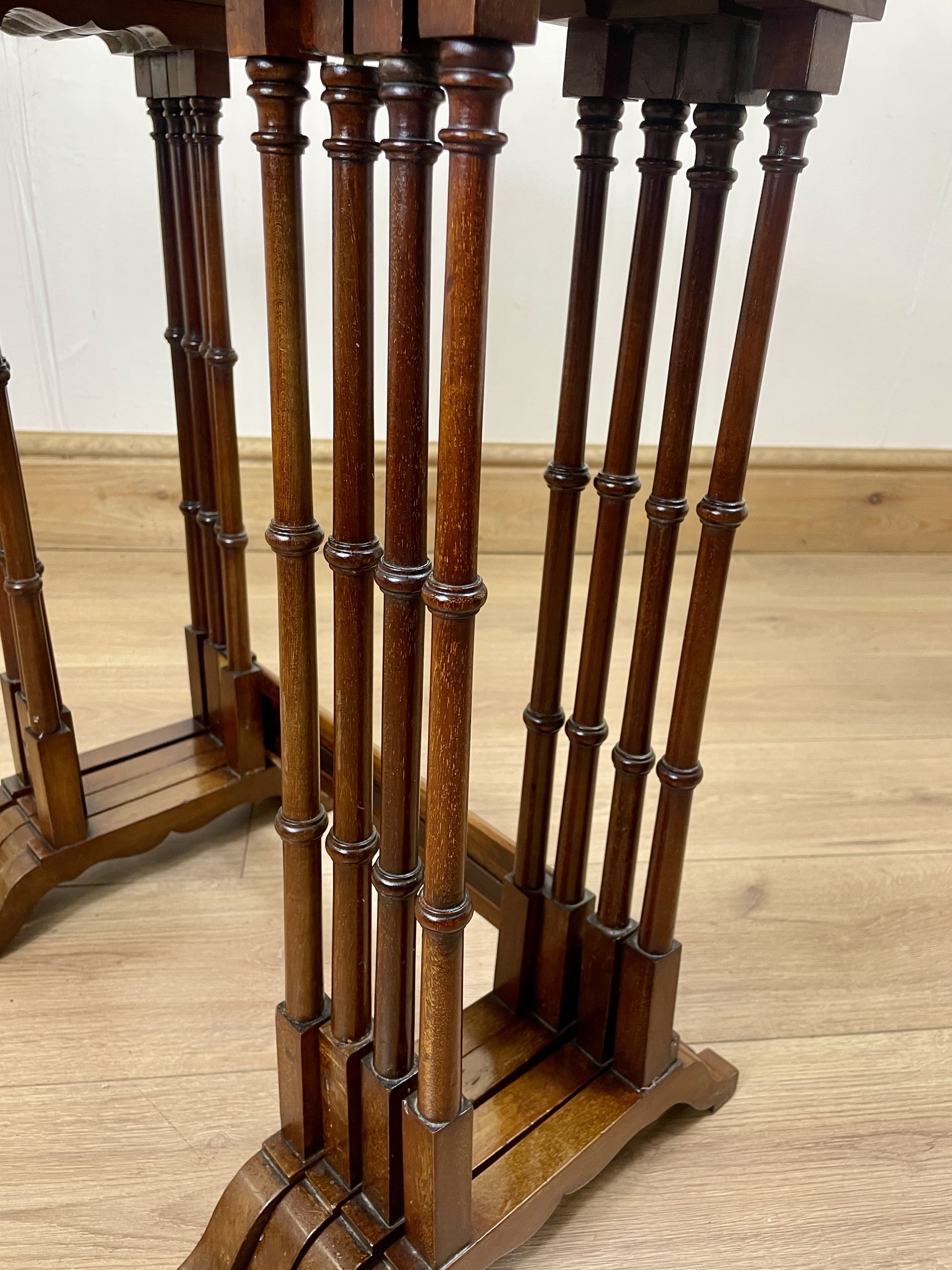 Wooden hat stand with multiple tiers on a wooden floor.