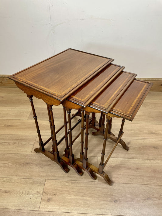 Set of three nested wooden tables on a wooden floor with a plain white wall background