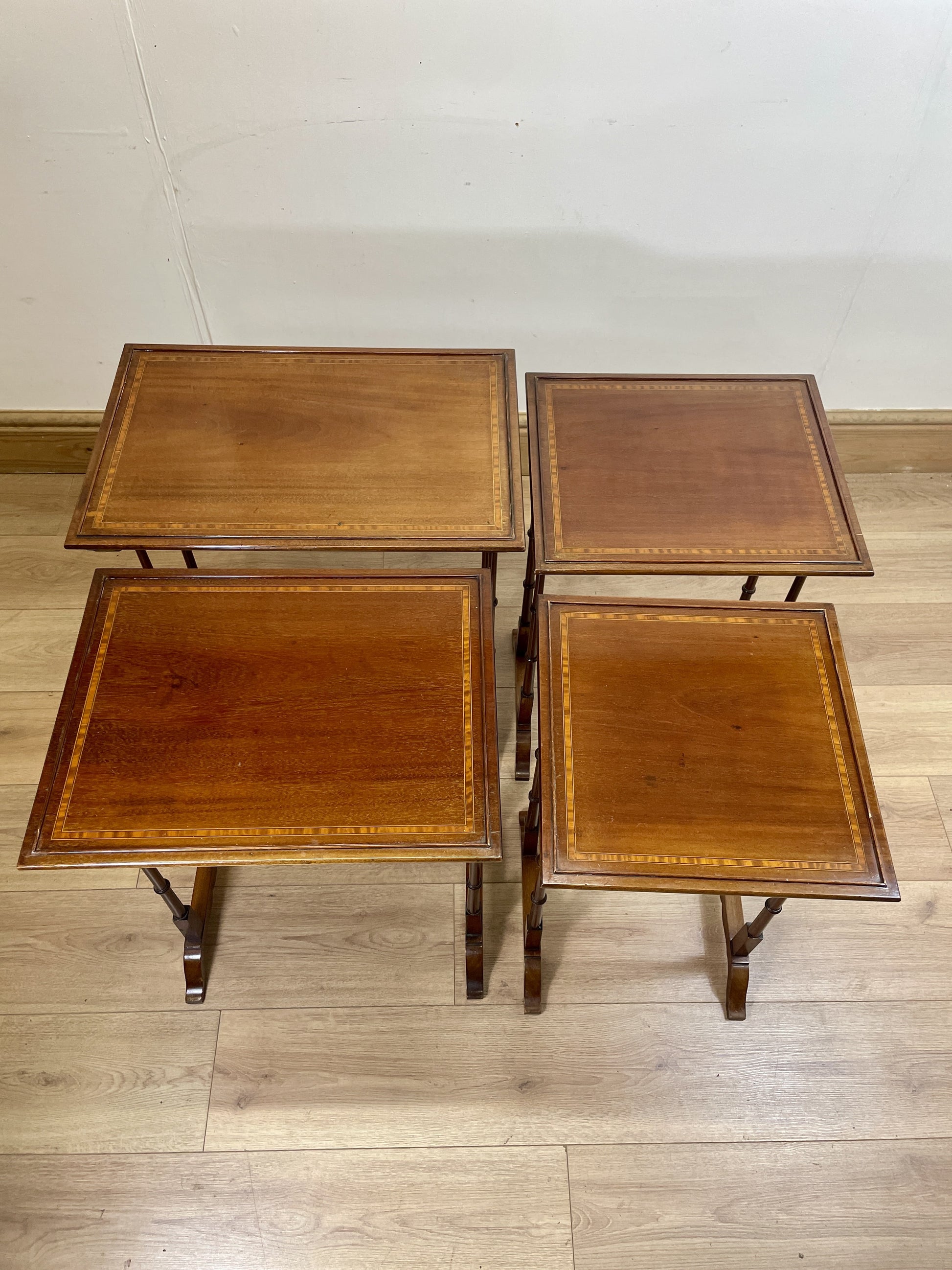 Set of four wooden nesting tables on a wooden floor.