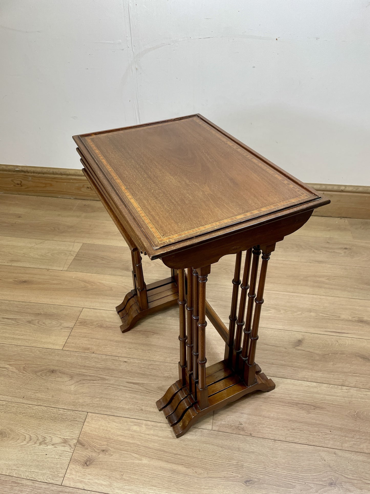 Wooden adjustable stand on a wooden floor with a white wall background