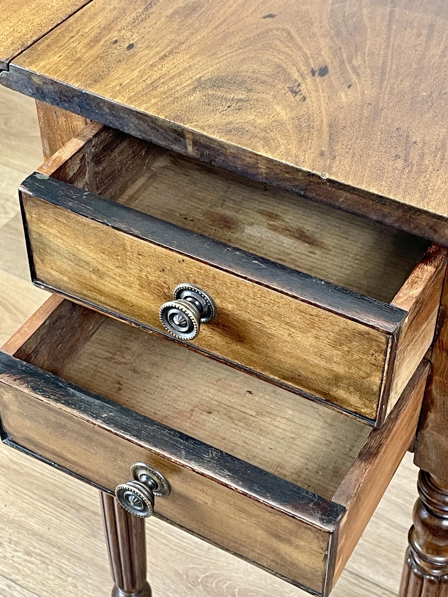 Wooden side table with two drawers on a wooden floor.