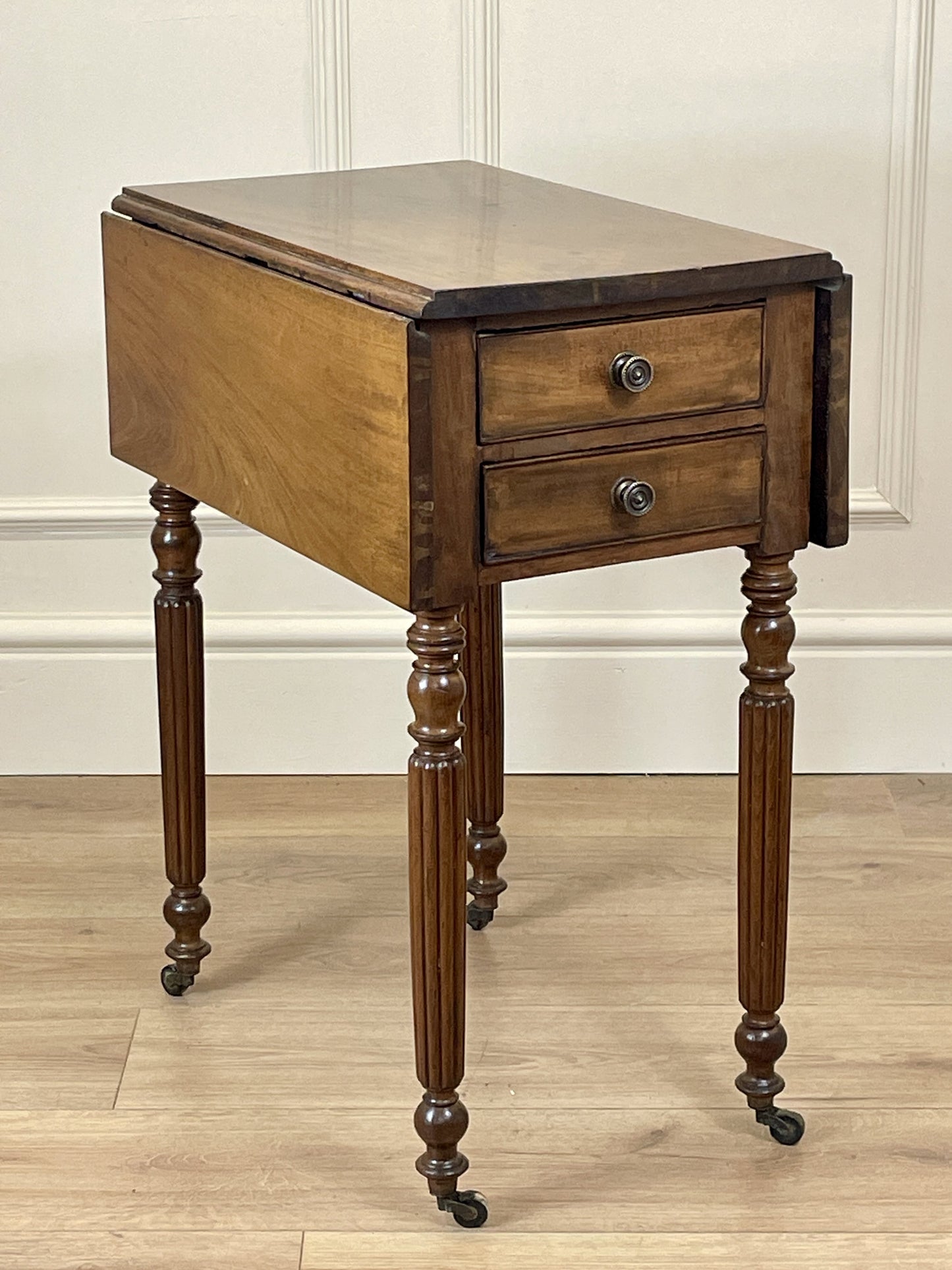 Wooden side table with two drawers on a wooden floor.