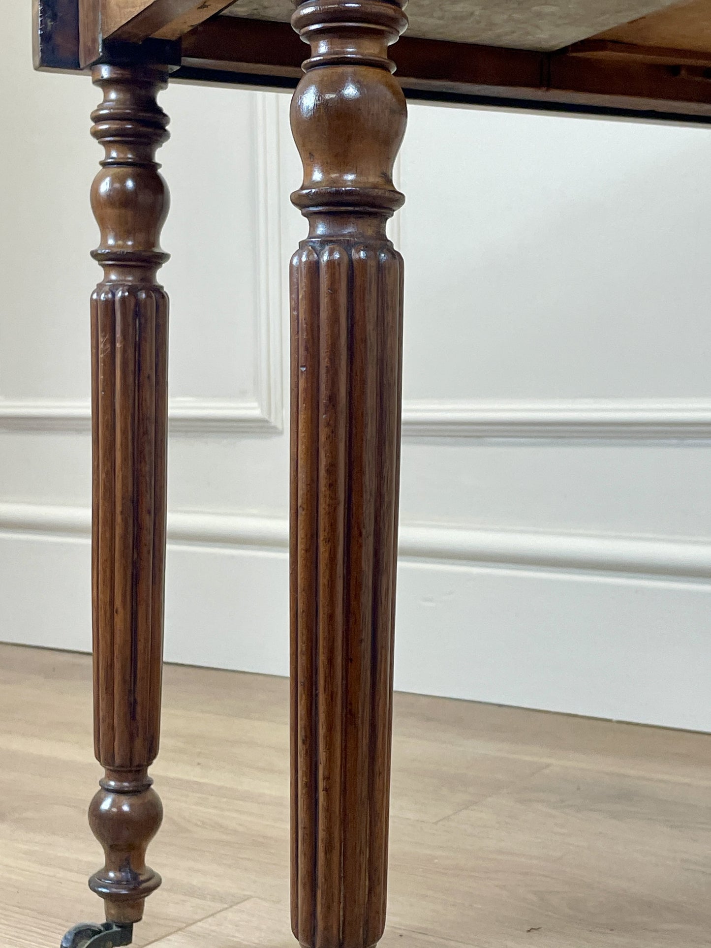 Close-up of wooden table legs against a white wall.