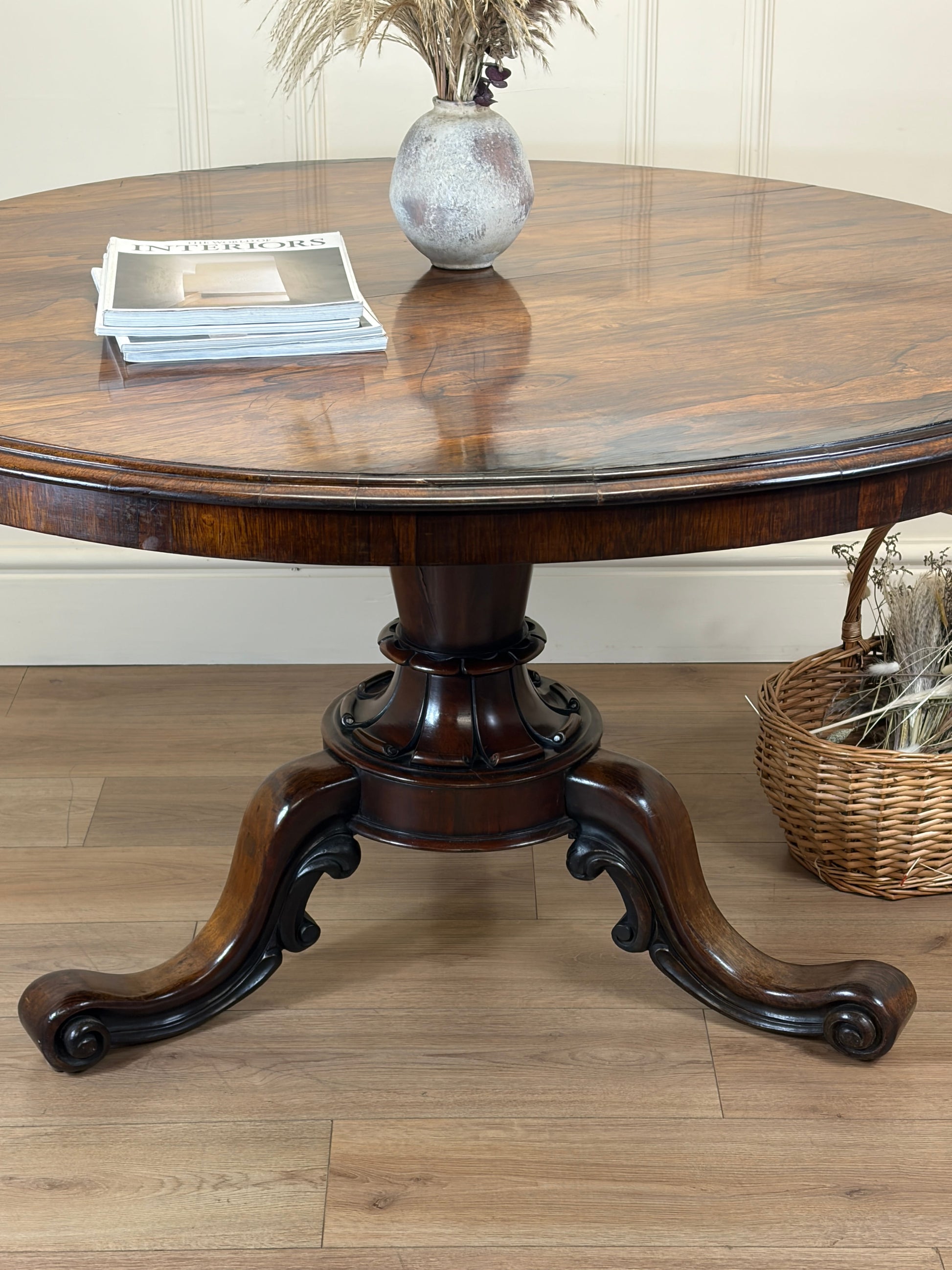 Wooden round table with a vase and books on a wooden floor