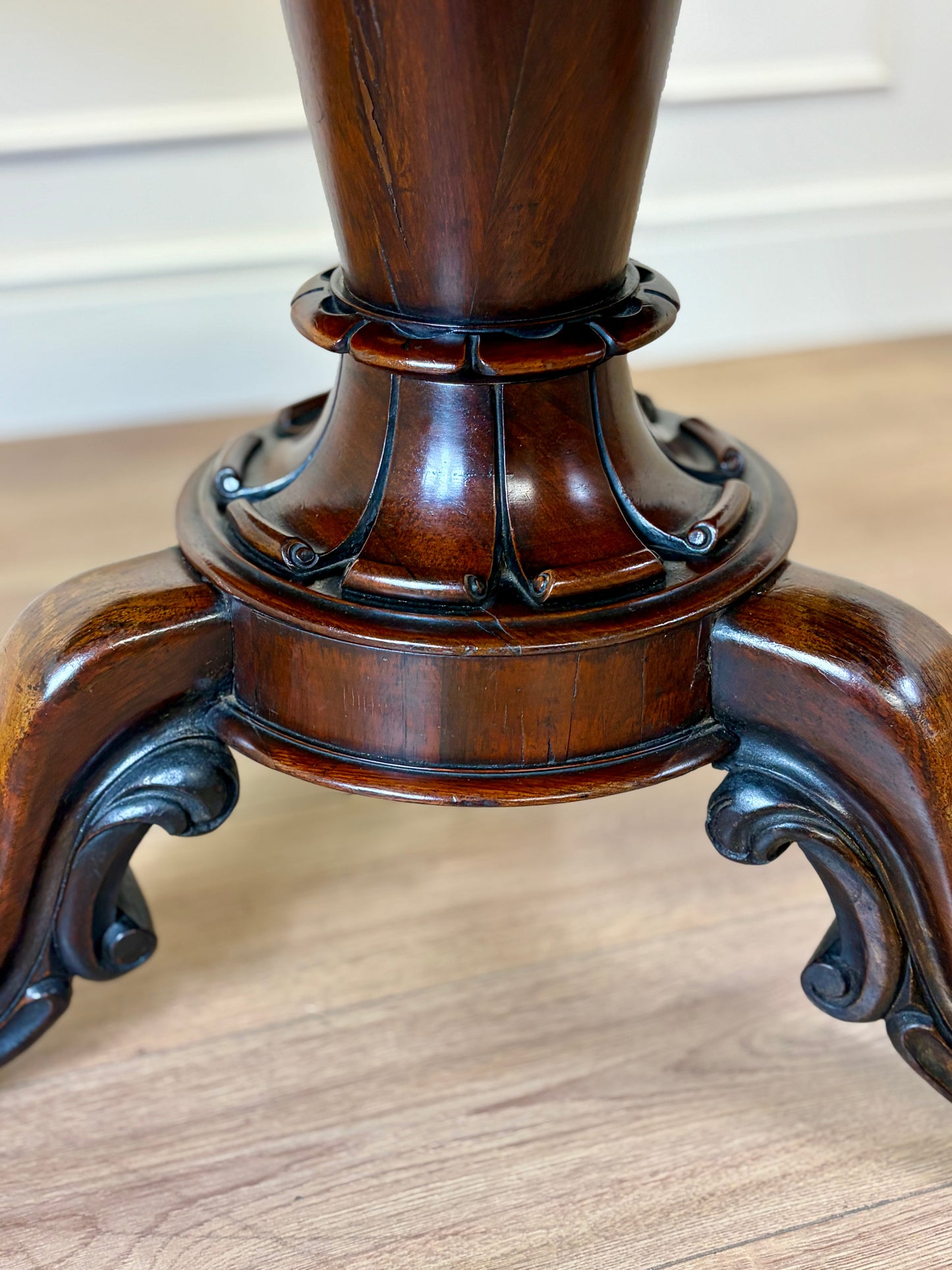 Close-up of a wooden pedestal with intricate carvings on a wooden floor.