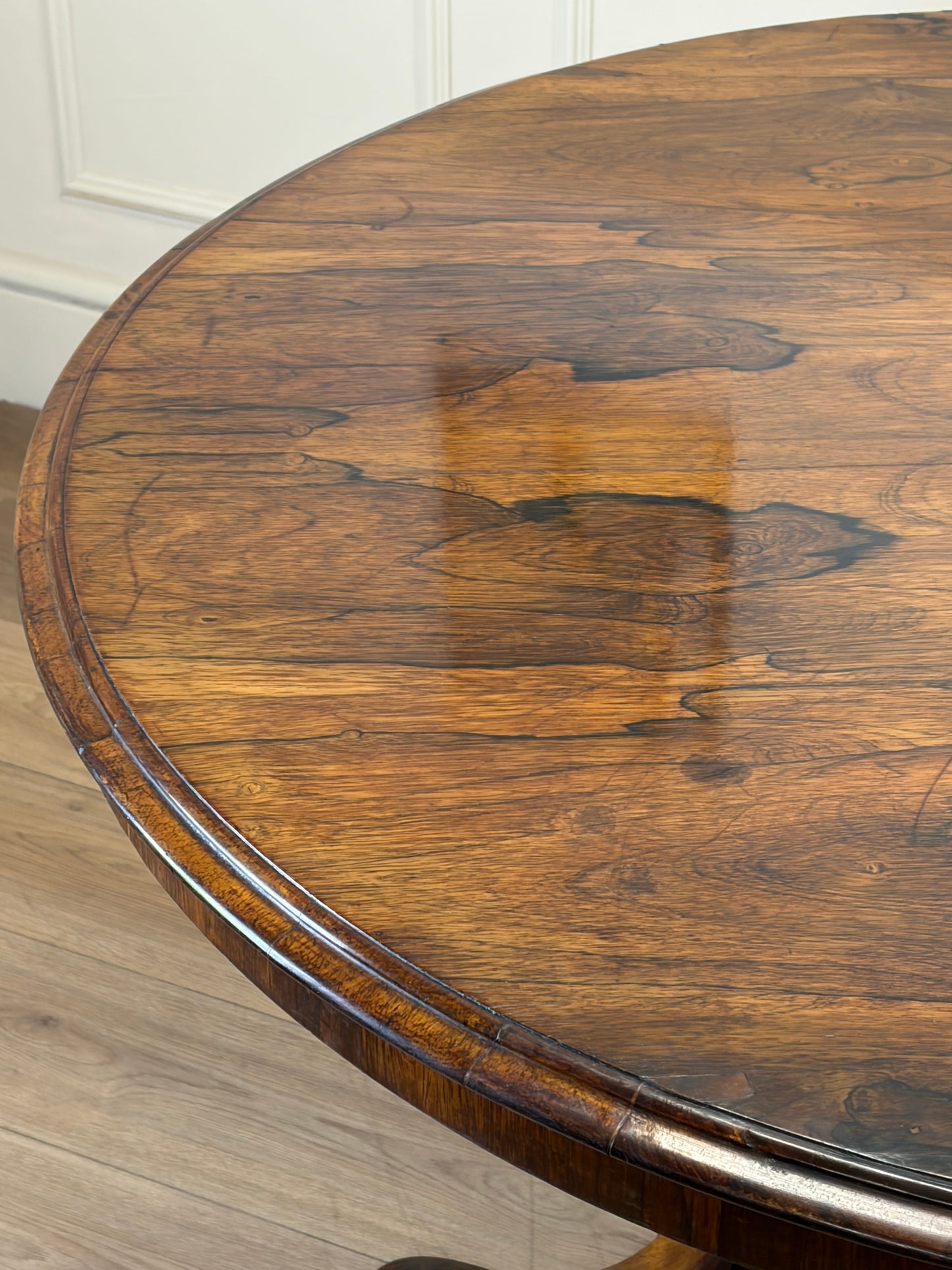 Round wooden table with a reflective surface on a light wood floor.
