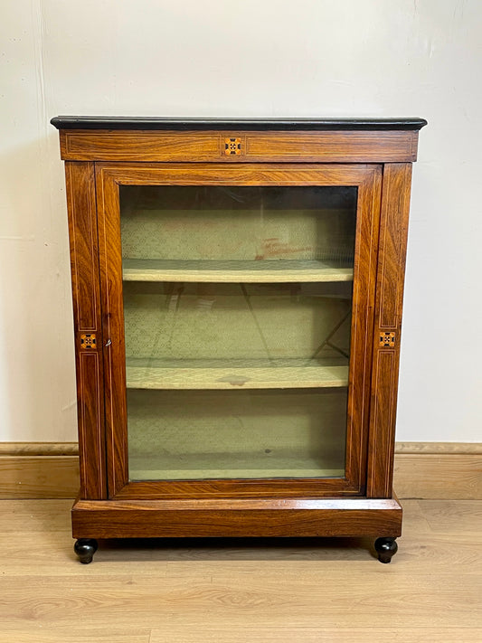 Wooden display cabinet with glass door on a wooden floor.