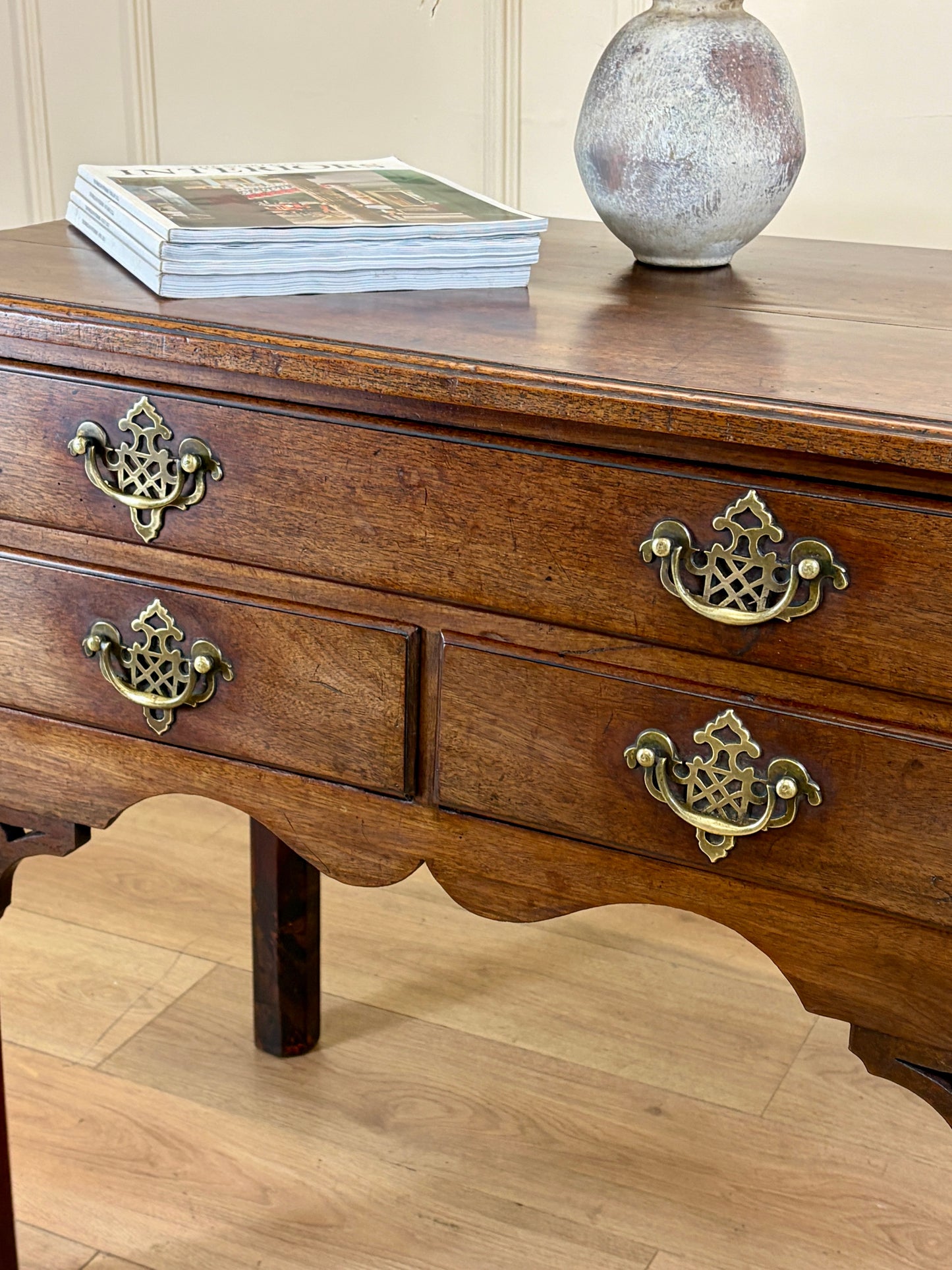 Wooden dresser with brass handles on a wooden floor