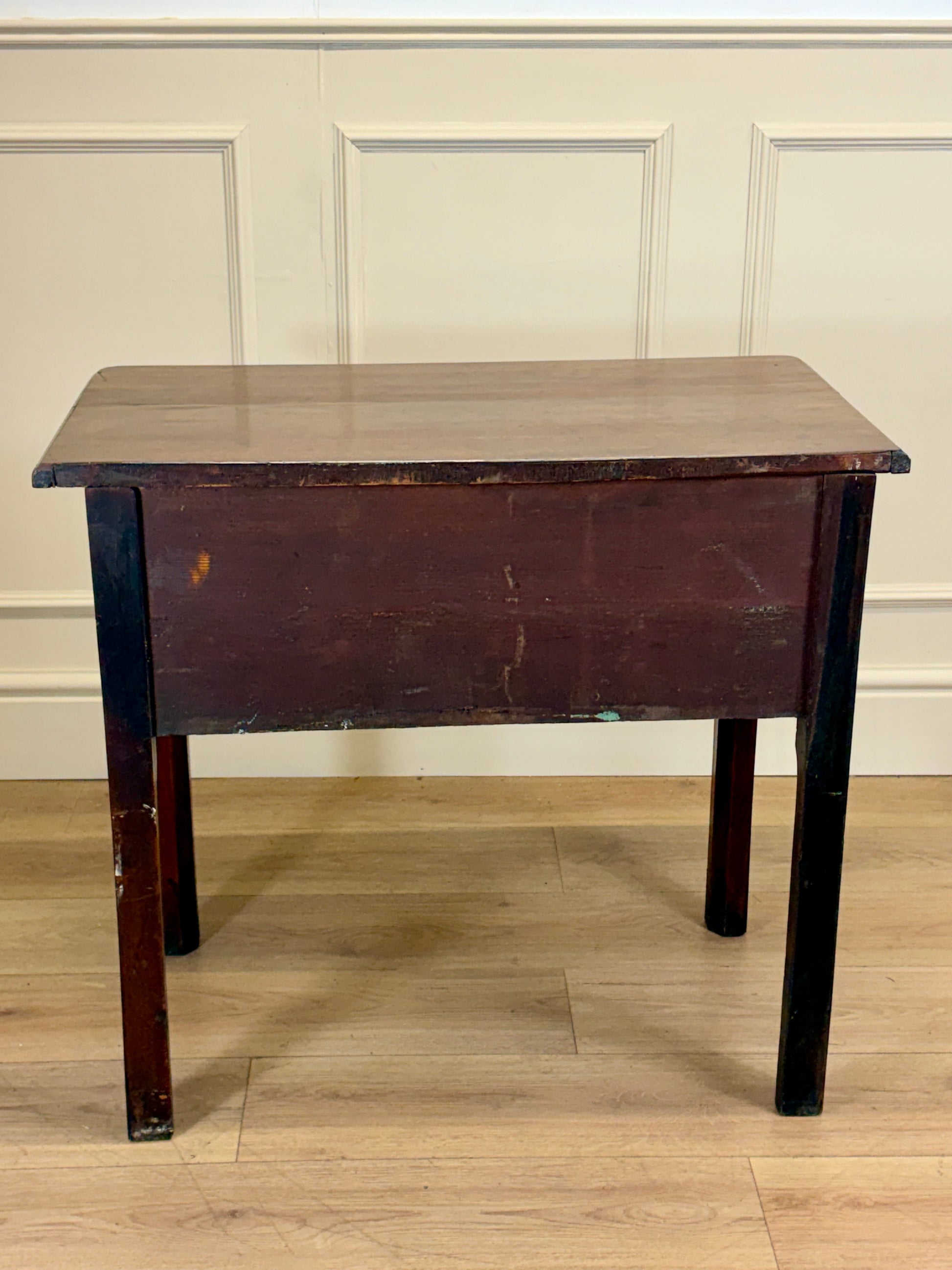 Wooden table with a dark finish against a white paneled wall.
