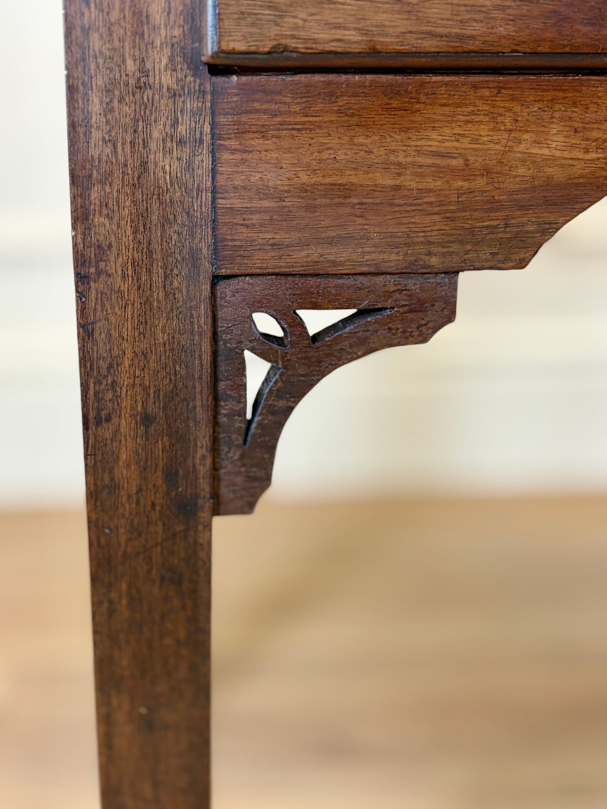 Close-up of a wooden chair leg with intricate carvings on a blurred background