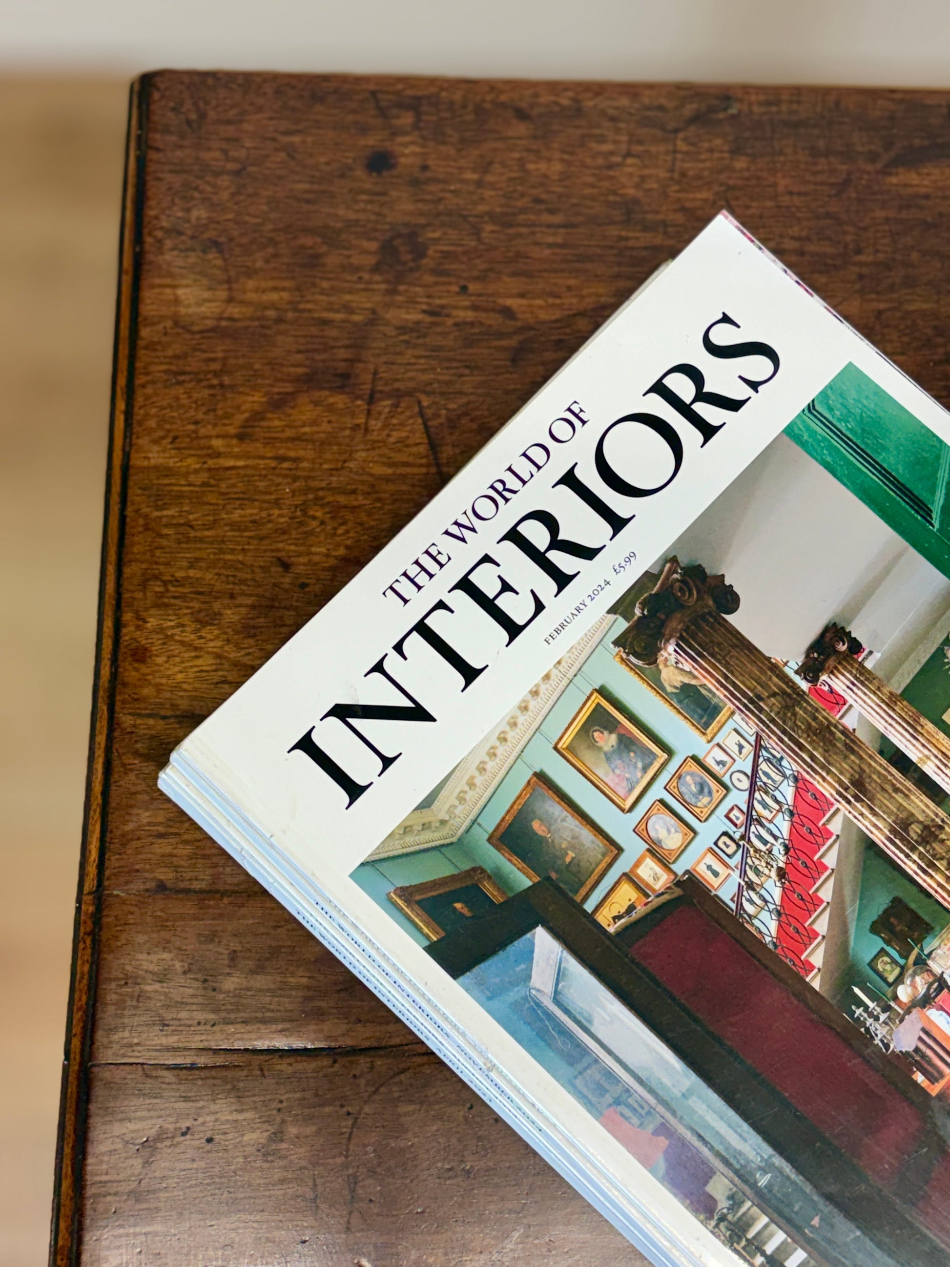 Book titled 'The World of Interiors' on a wooden surface