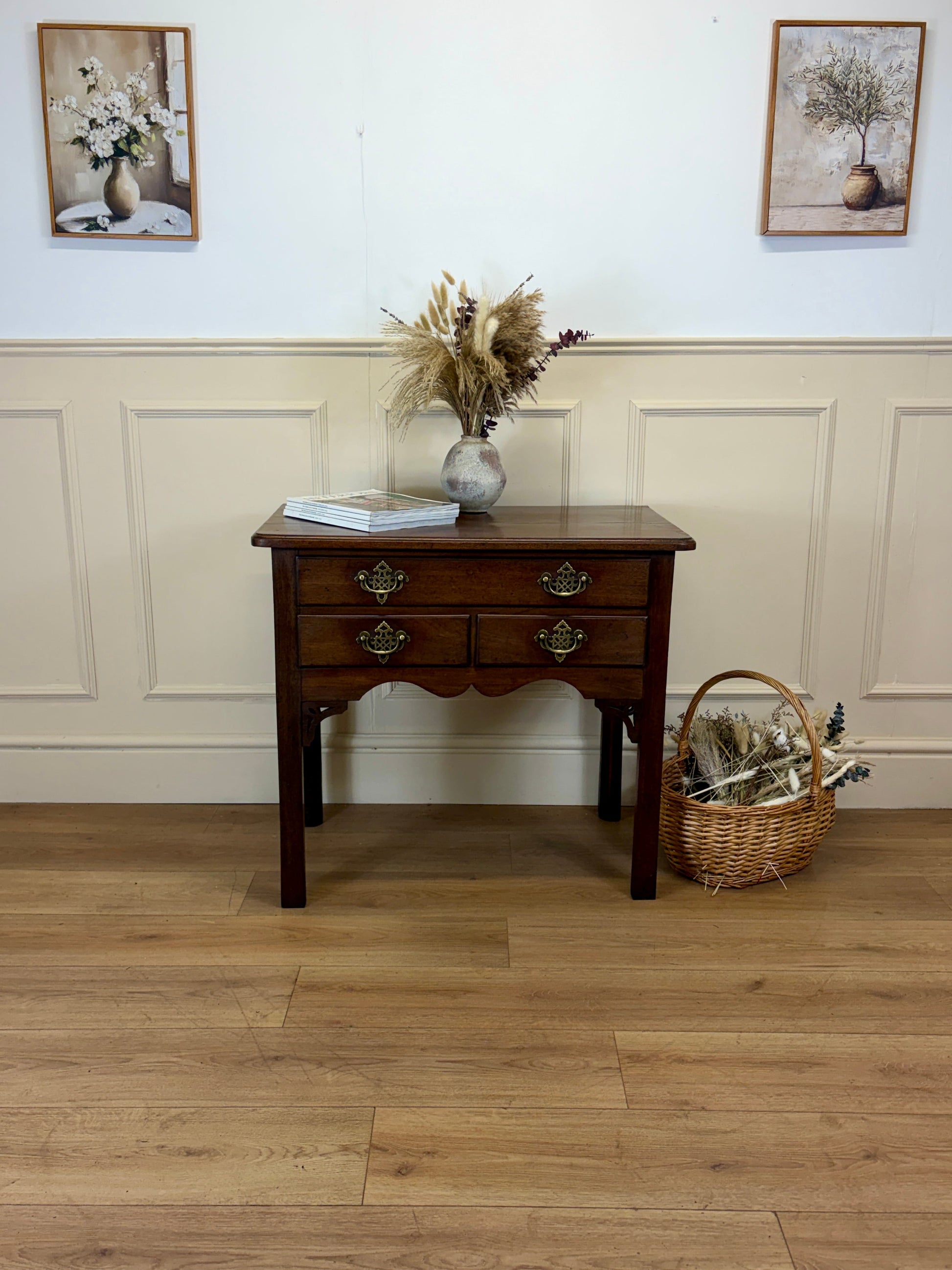 Wooden side table with decorative items against a white paneled wall.
