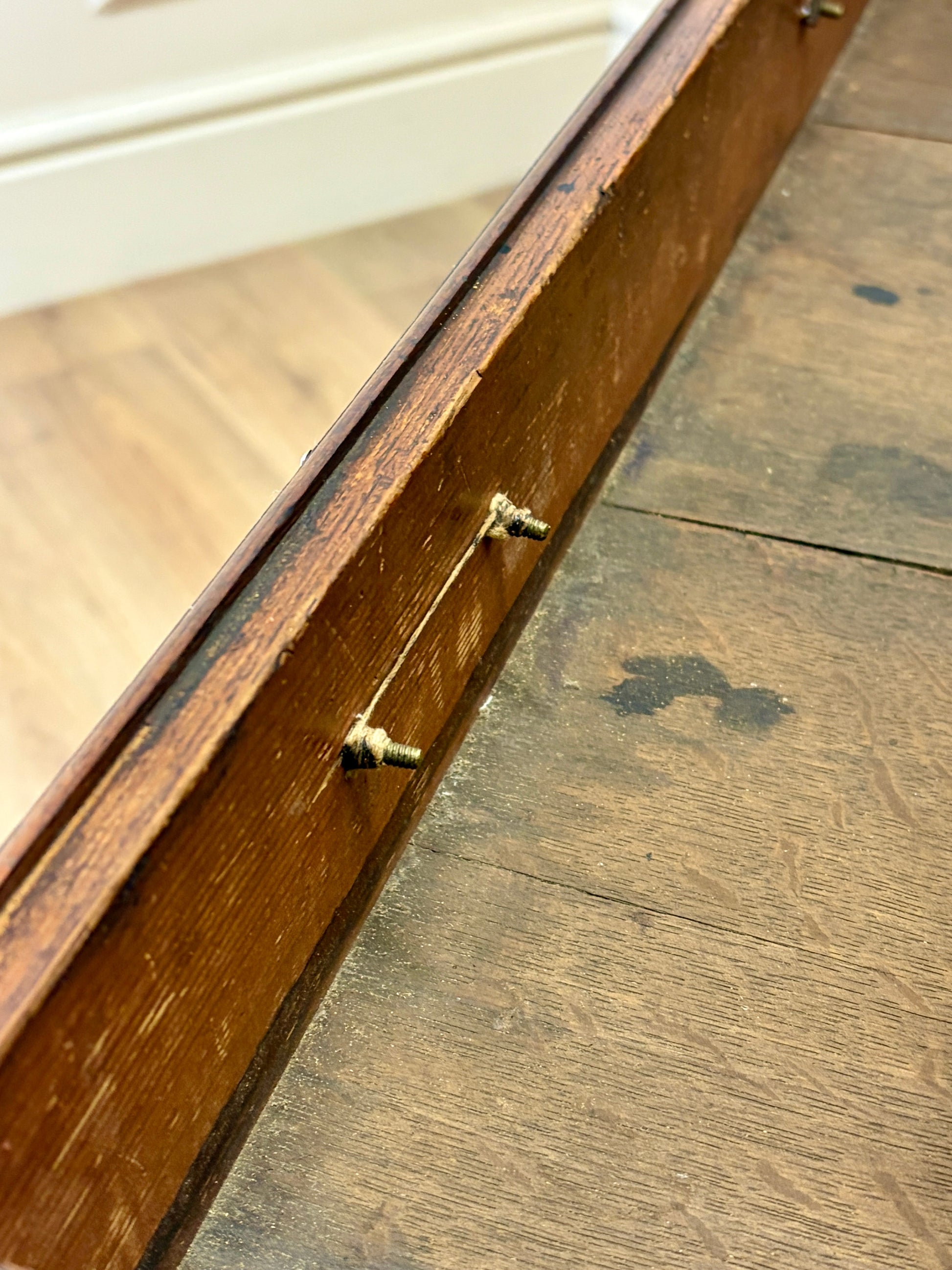 Wooden drawer with a gold handle on a wooden floor.