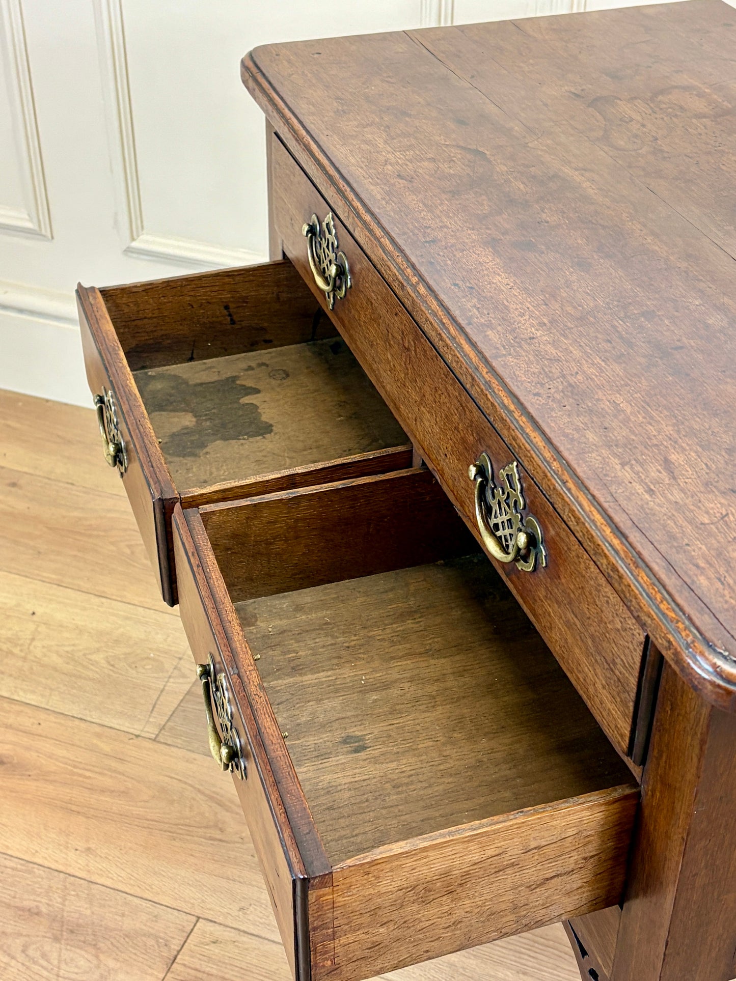 Wooden desk with open drawers on a wooden floor.