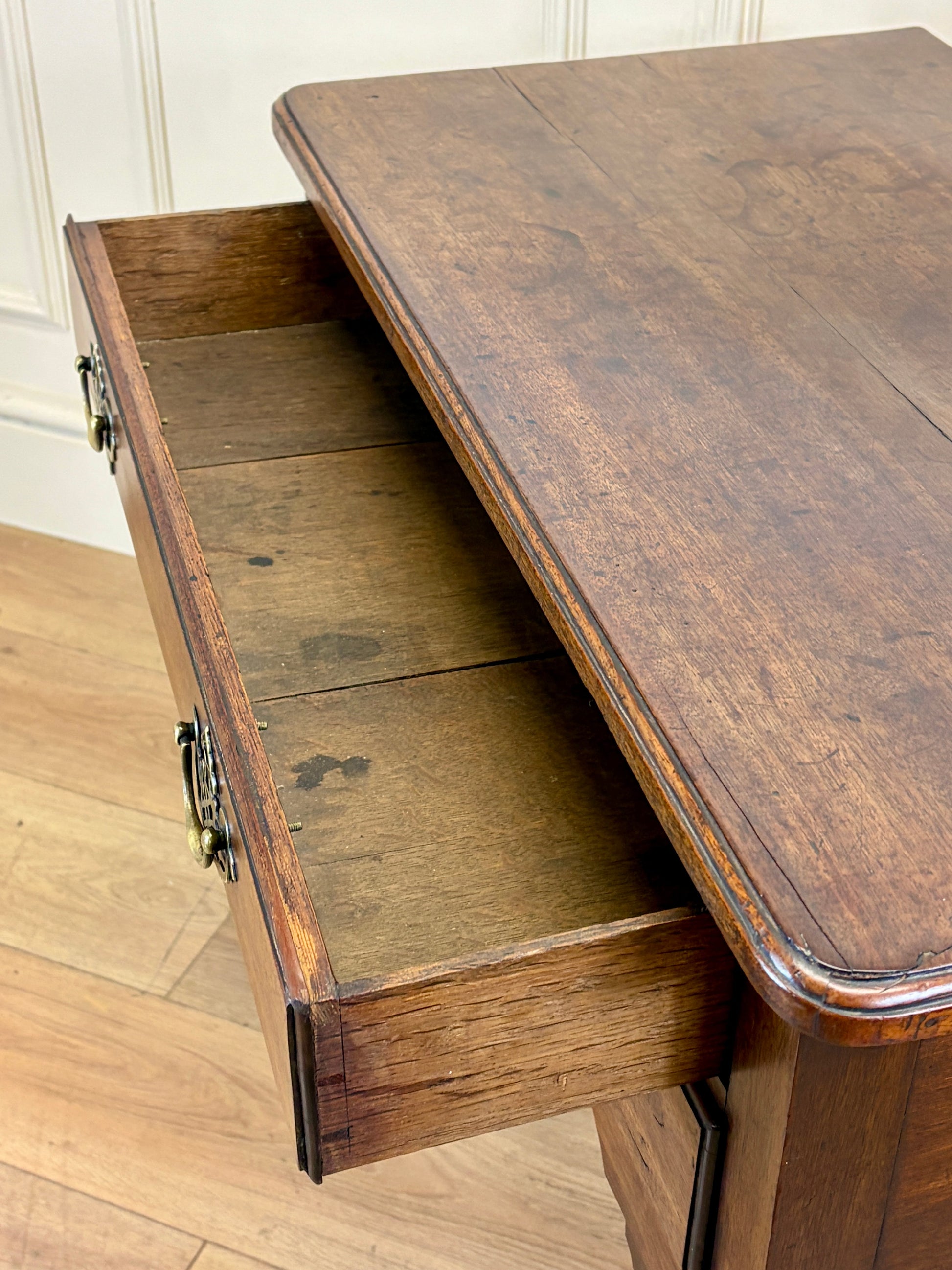 Wooden desk with an open drawer on a wooden floor.