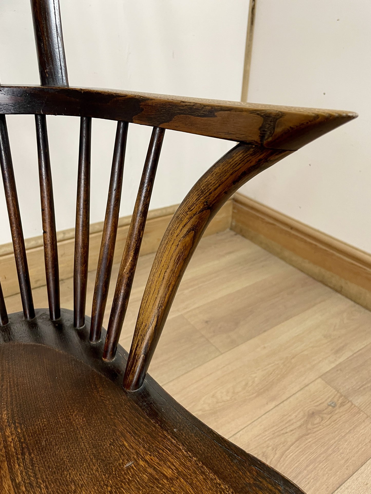 Close-up of a wooden chair with a wavy leg design on a wooden floor.