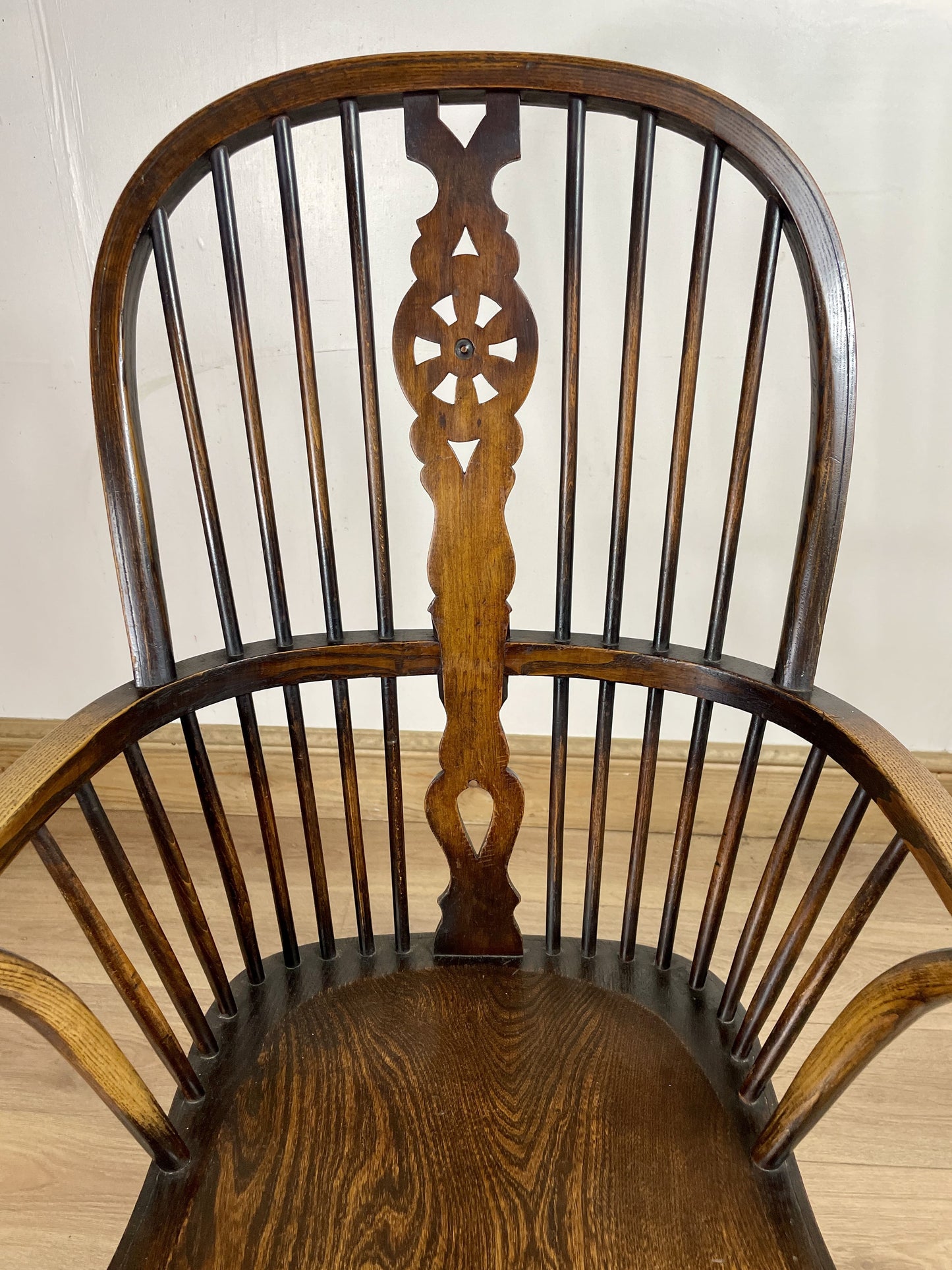 Wooden chair with intricate back design on a wooden floor.