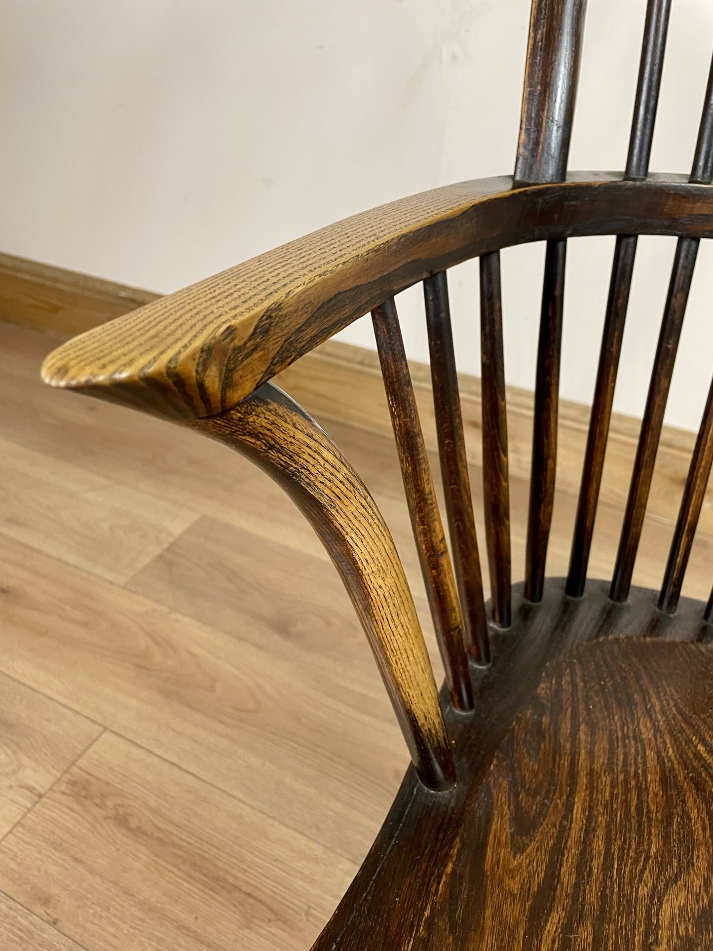 Wooden chair with curved armrest on a wooden floor