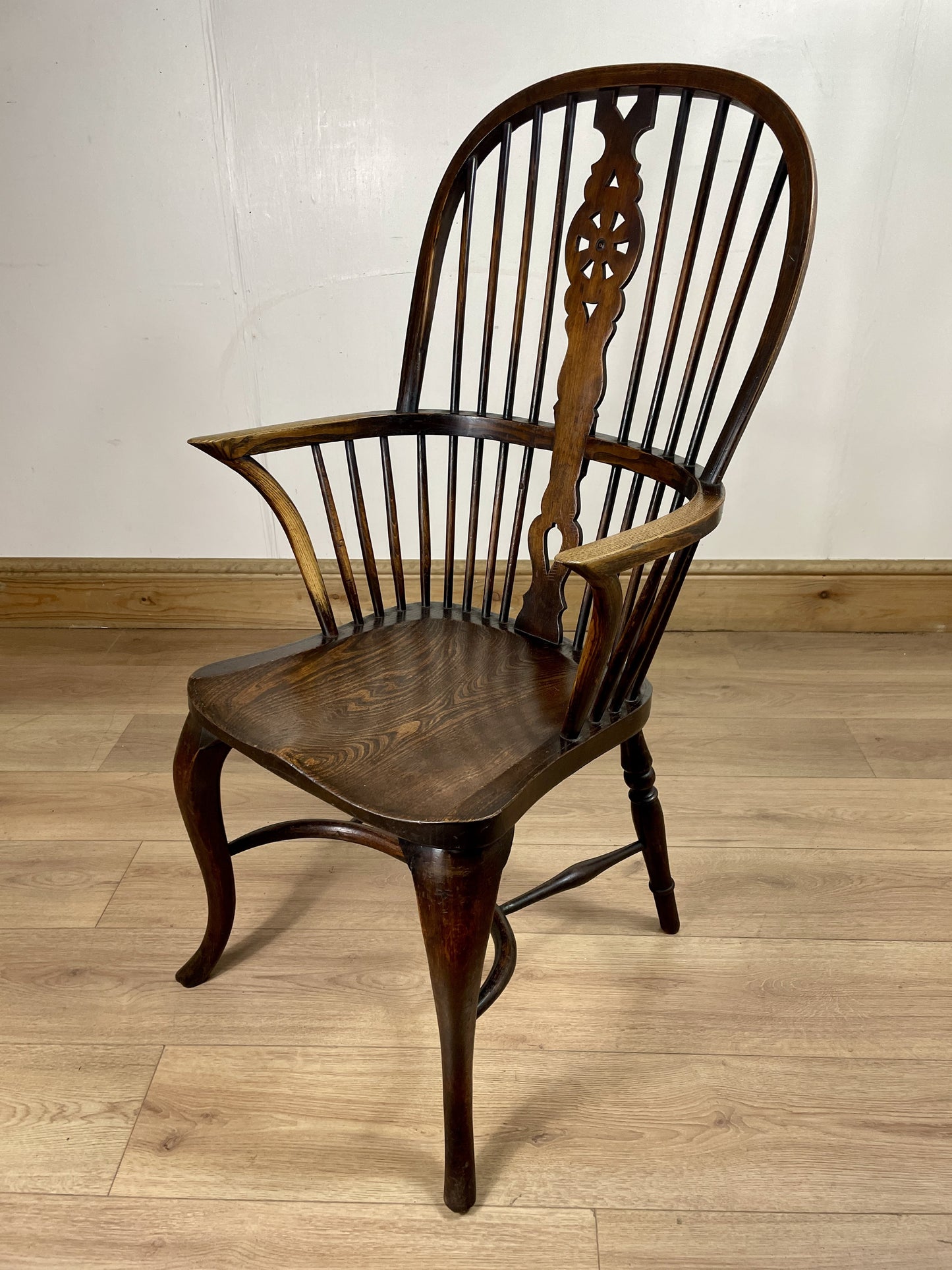 Wooden armchair with intricate back design on a wooden floor.