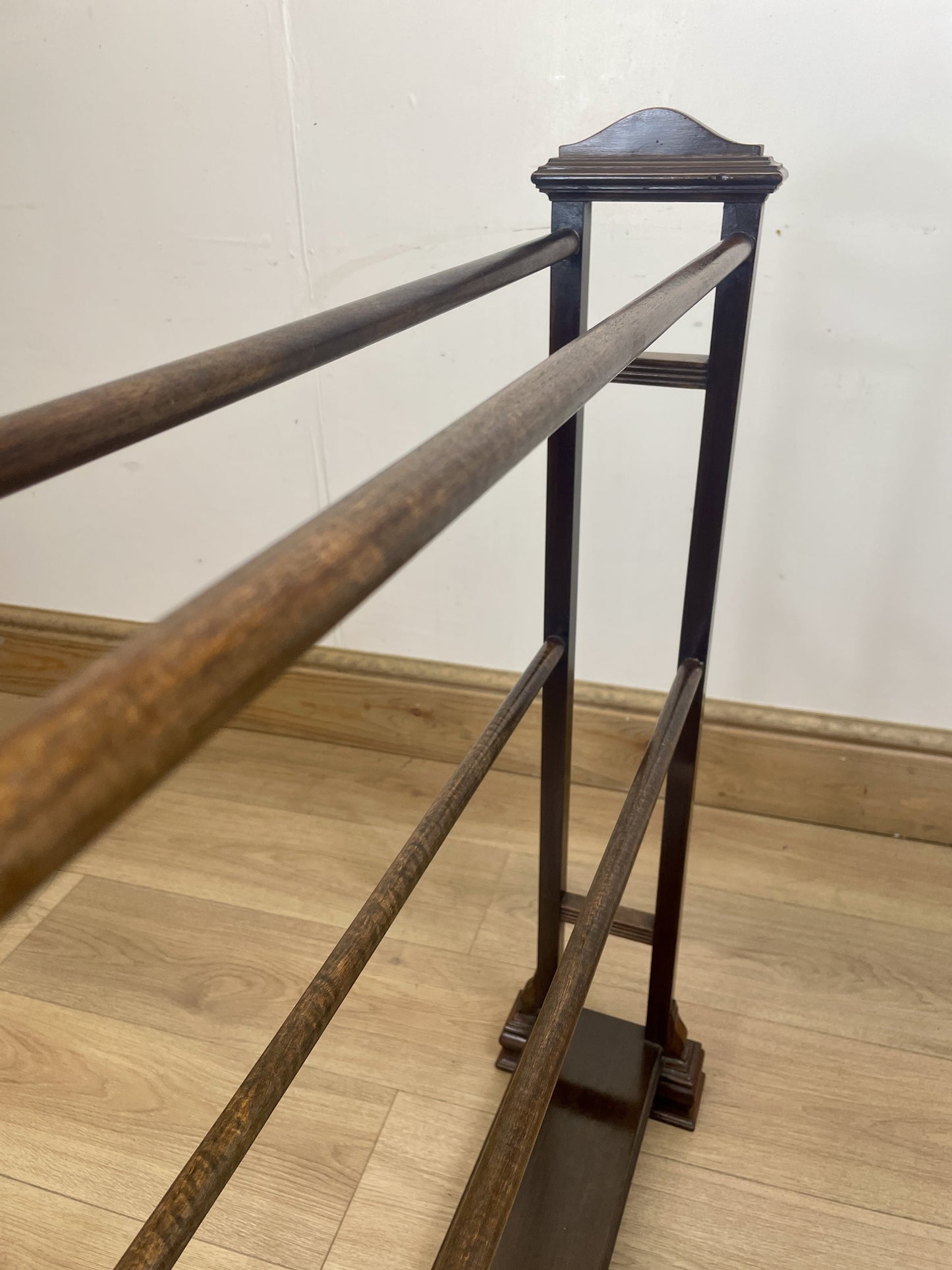 Wooden and metal railing on a wooden floor with a white wall background