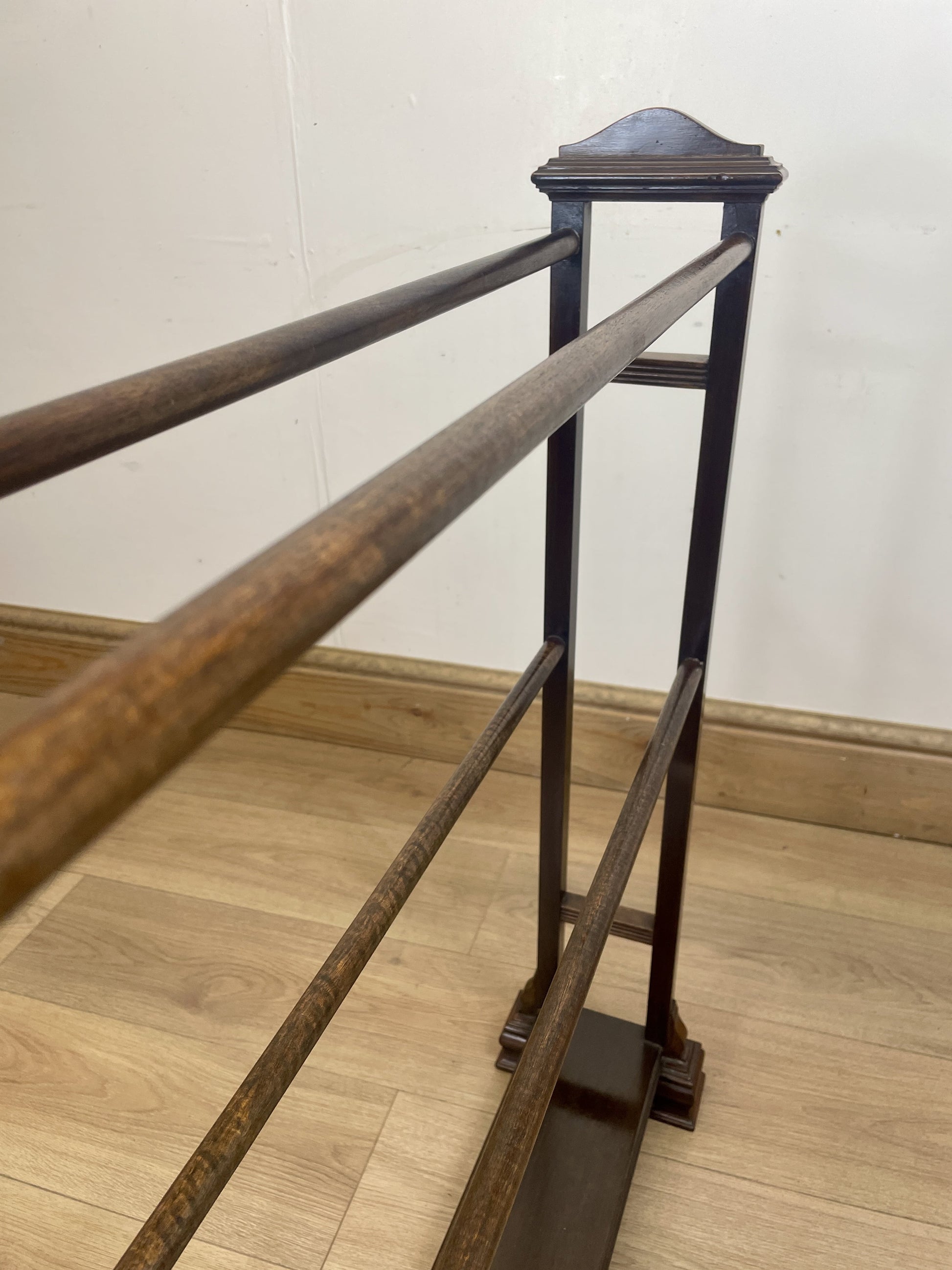 Wooden and metal railing on a wooden floor with a white wall background
