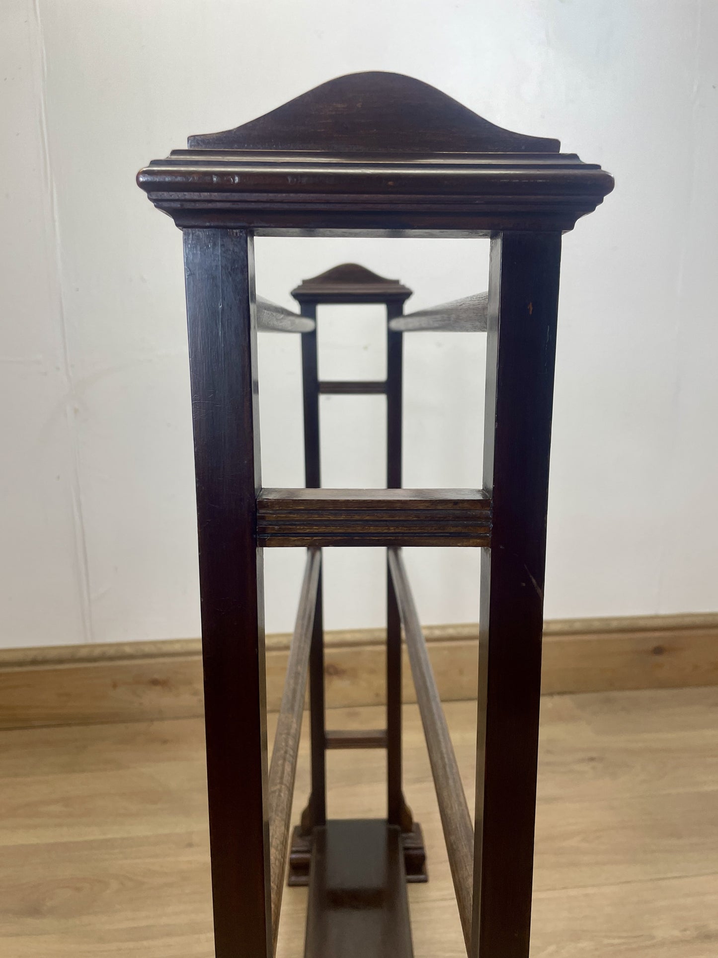 Dark wooden pedestal with glass front on a light wood floor.