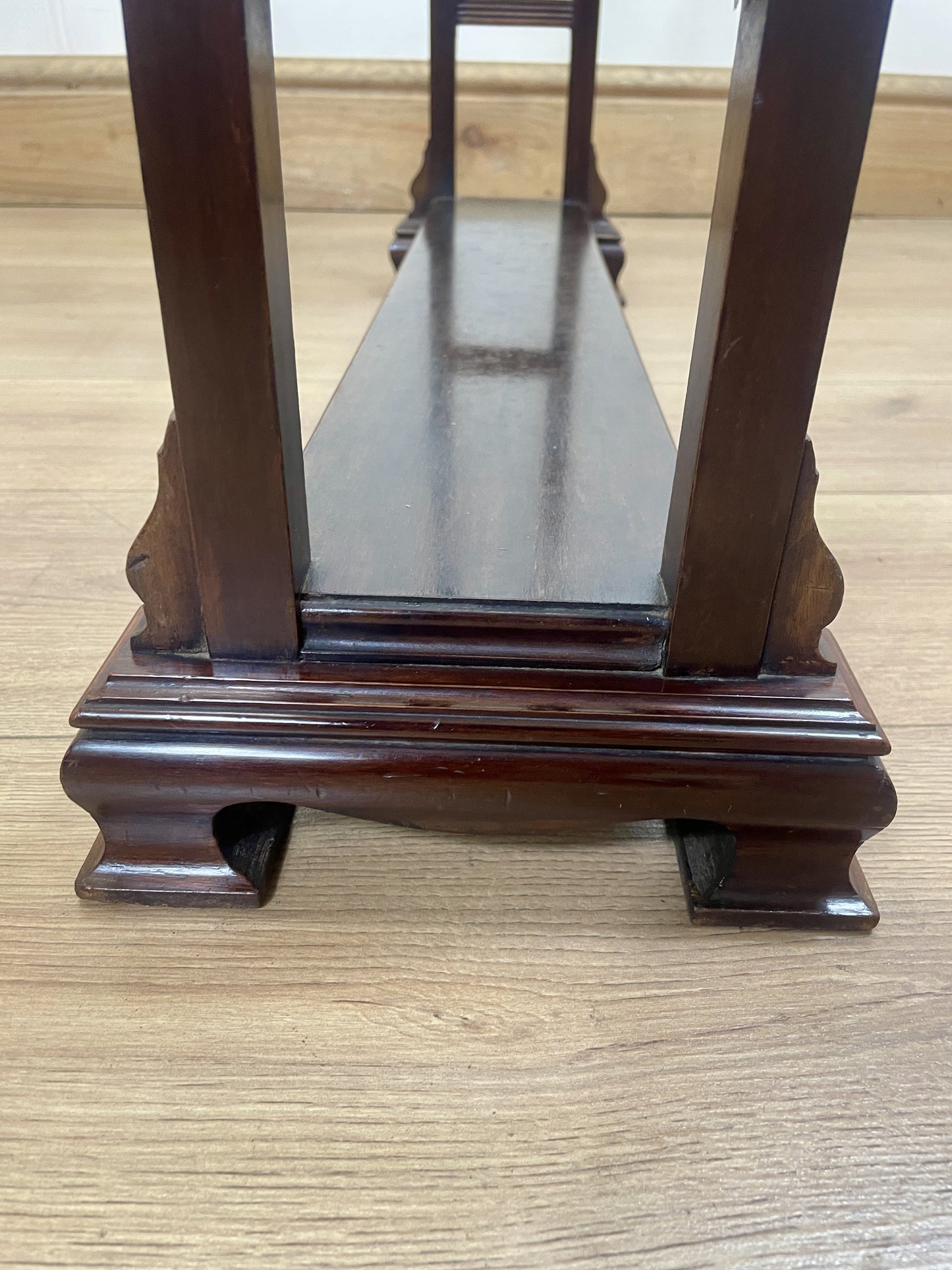 Wooden display stand with glass top on a wooden floor